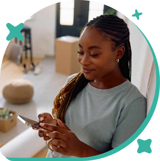 A woman with braided hair looking at her phone inside a modern living room.