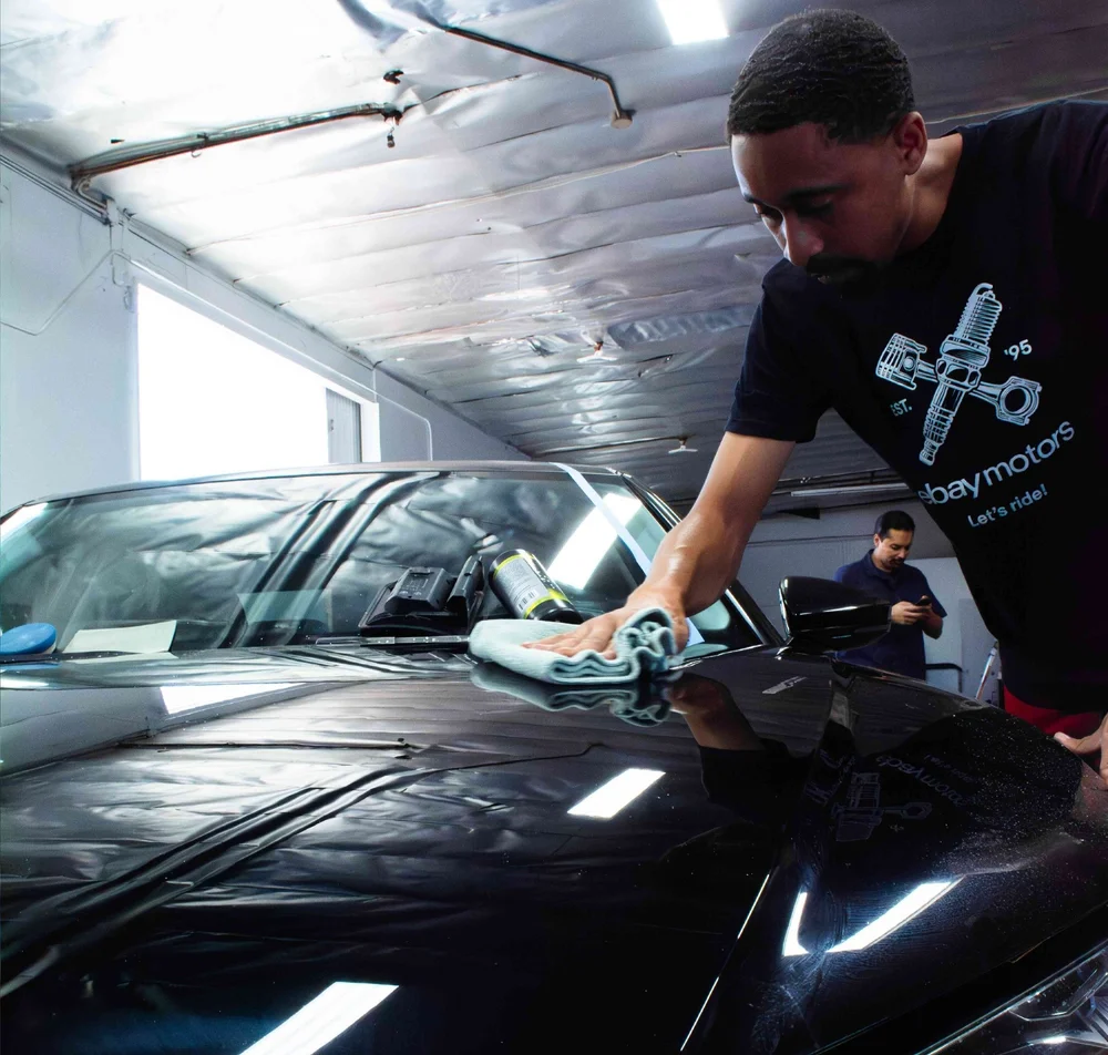 A team member carefully hand washing a luxury vehicle at the studio.