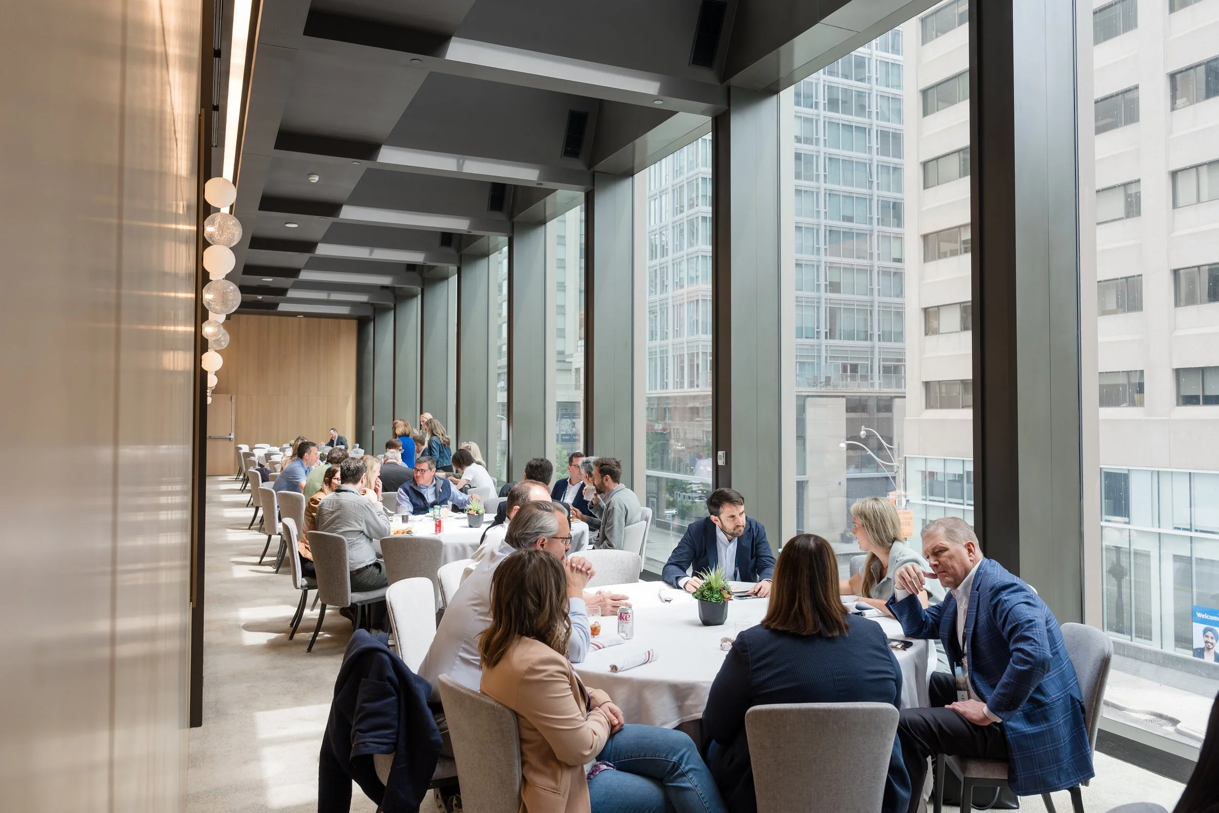 Networking and discussions in an open event space with large windows overlooking the city at Park Hyatt Toronto.