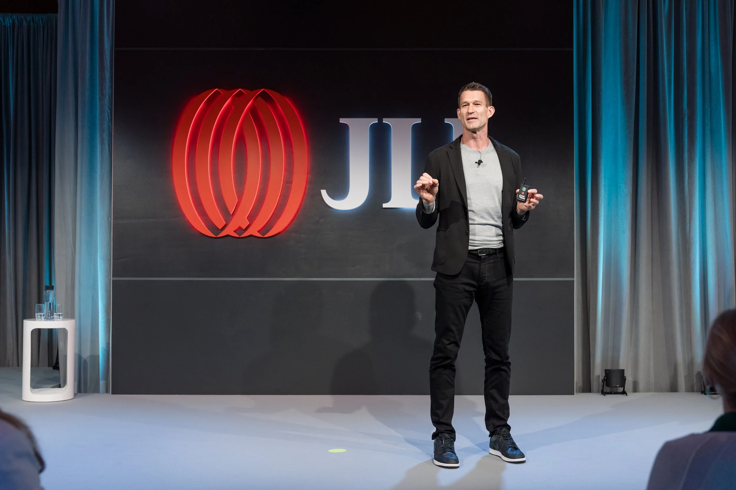 Speaker presenting at the JLL Global Leadership Meeting 2024 at Park Hyatt Toronto with the JLL logo in the background.