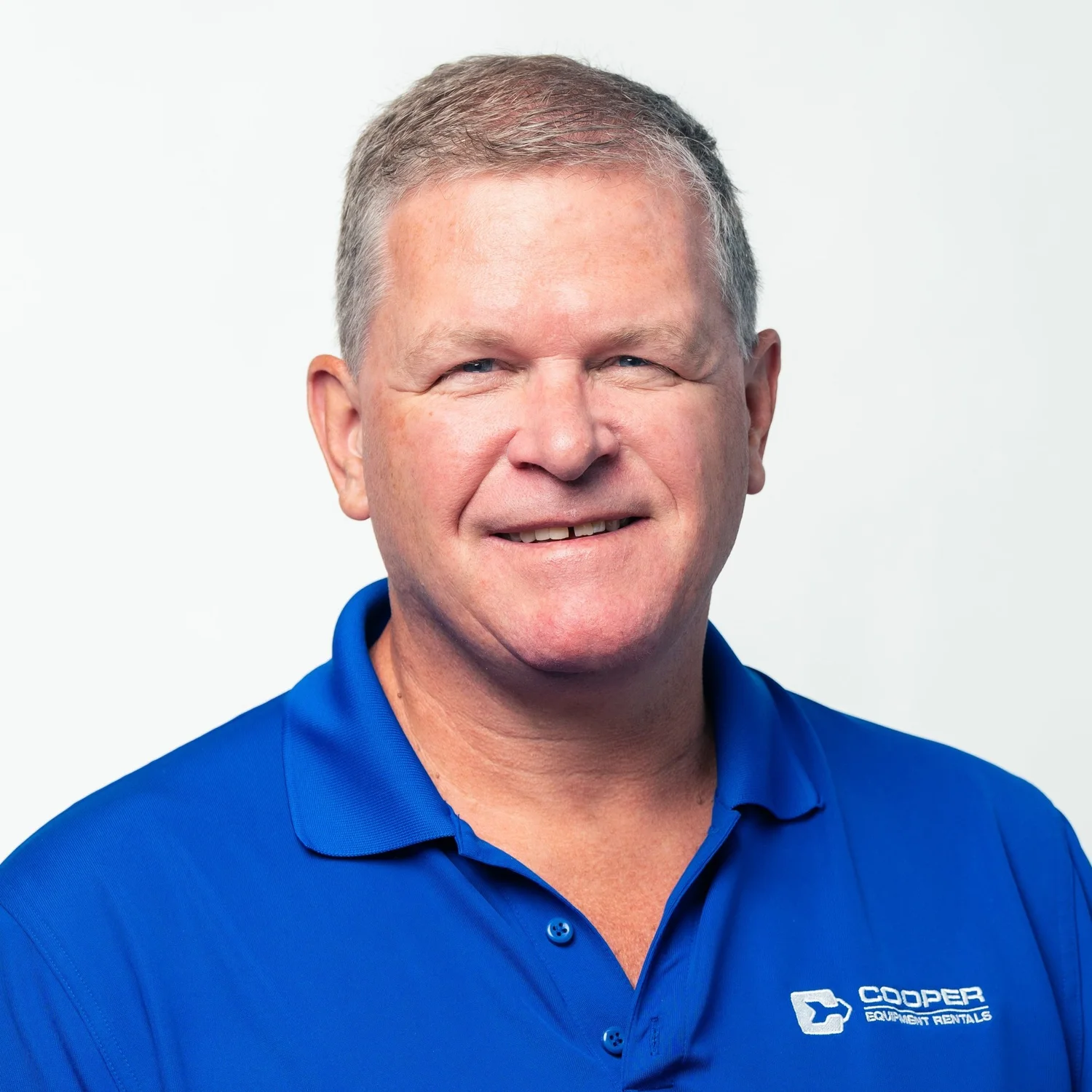 Person wearing a blue Cooper Equipment Rentals polo shirt, smiling at the camera against a plain background.