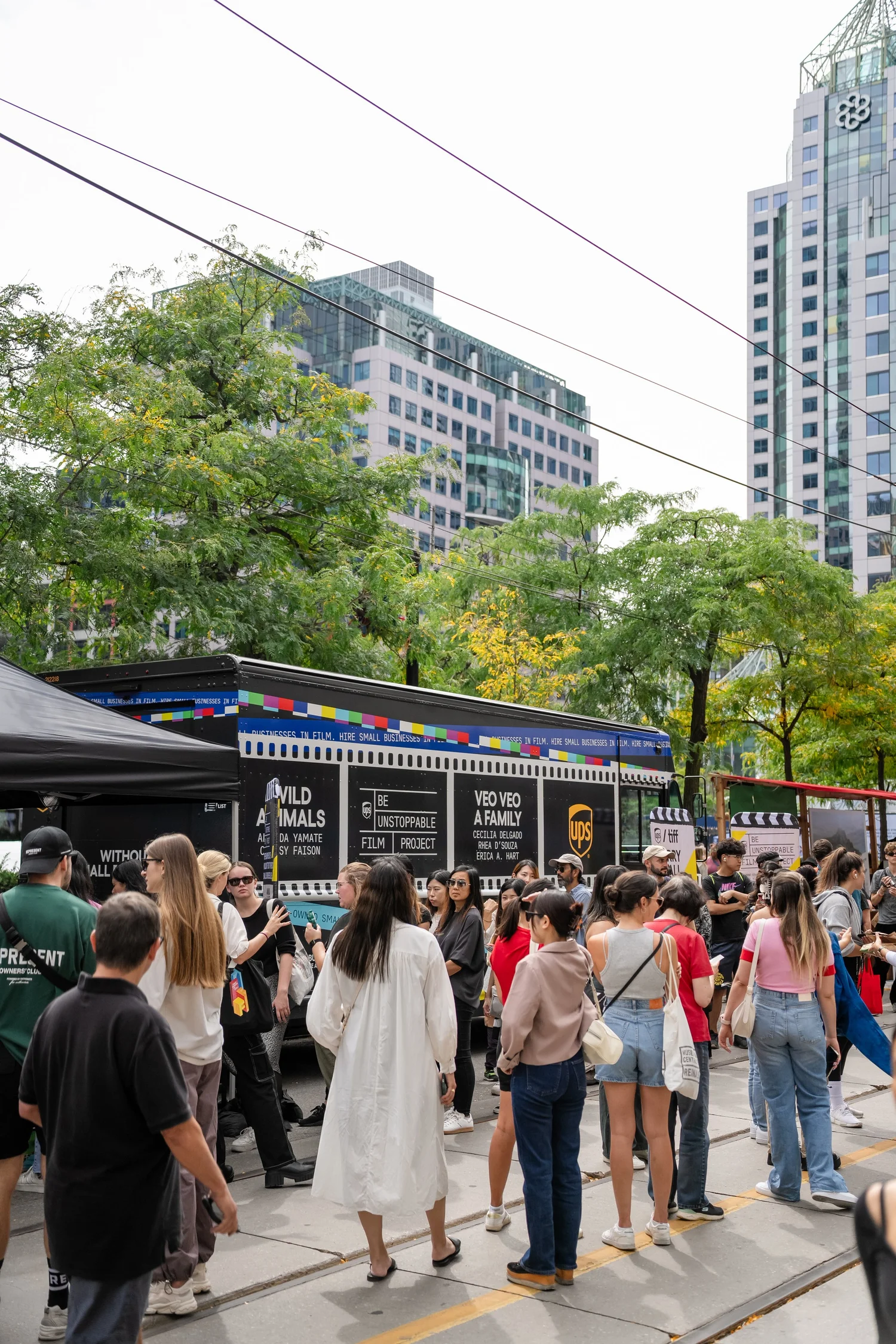 Crowd gathered near a film-themed truck in an urban area