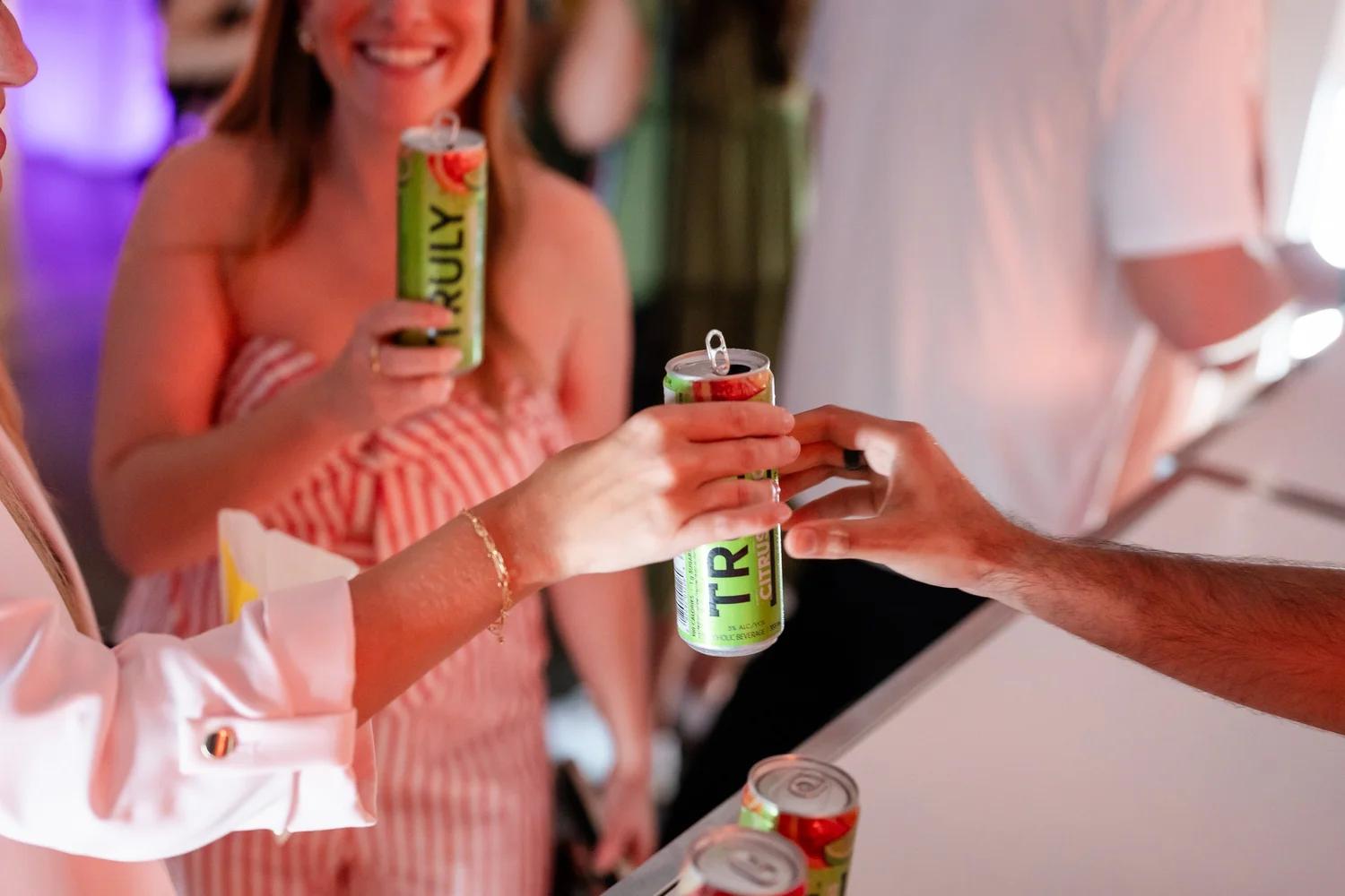 People exchanging Truly hard seltzer cans at a social event.