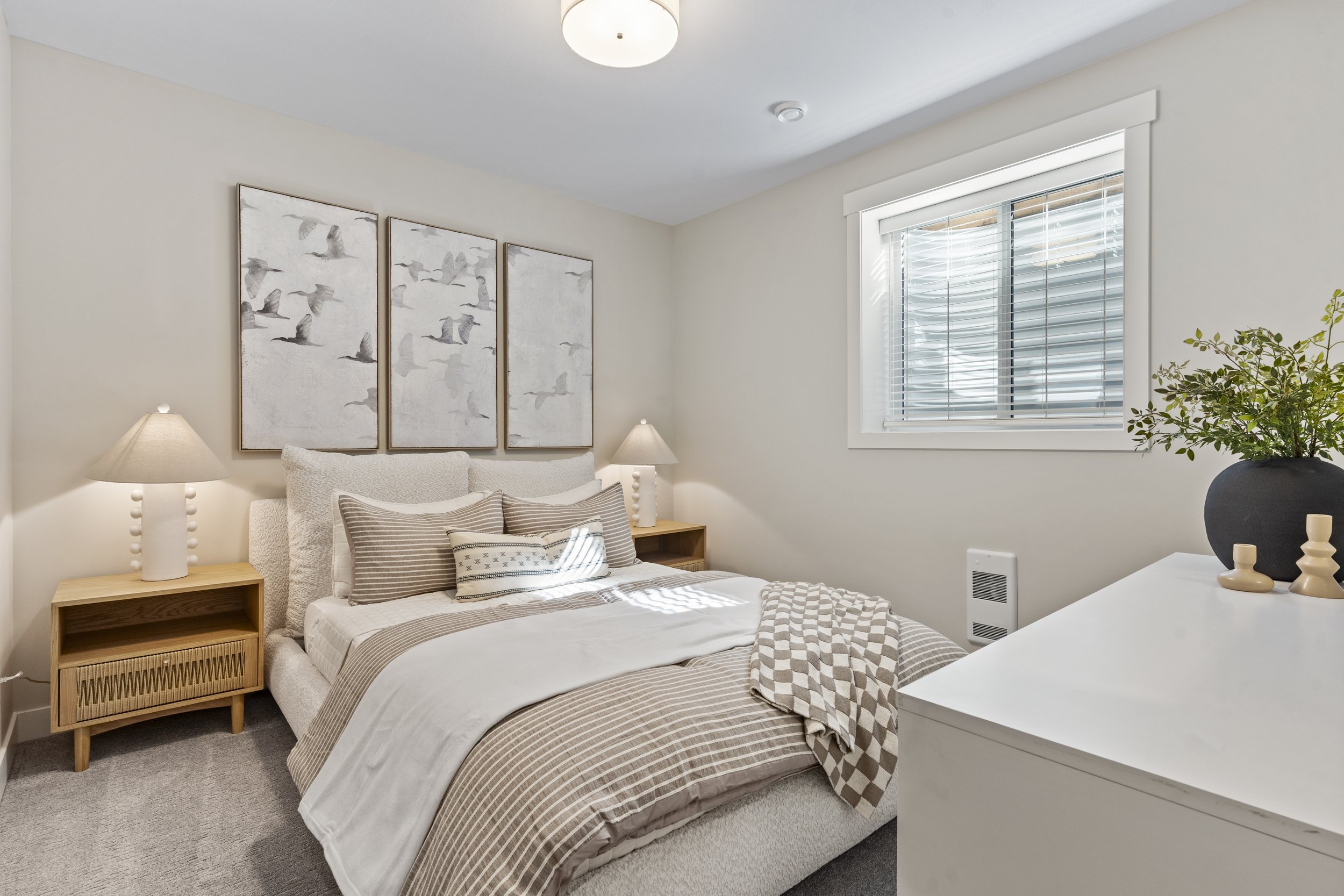 Photo of a bright and spacious suite bedroom featuring a large window, natural light, and a warm, cozy atmosphere.