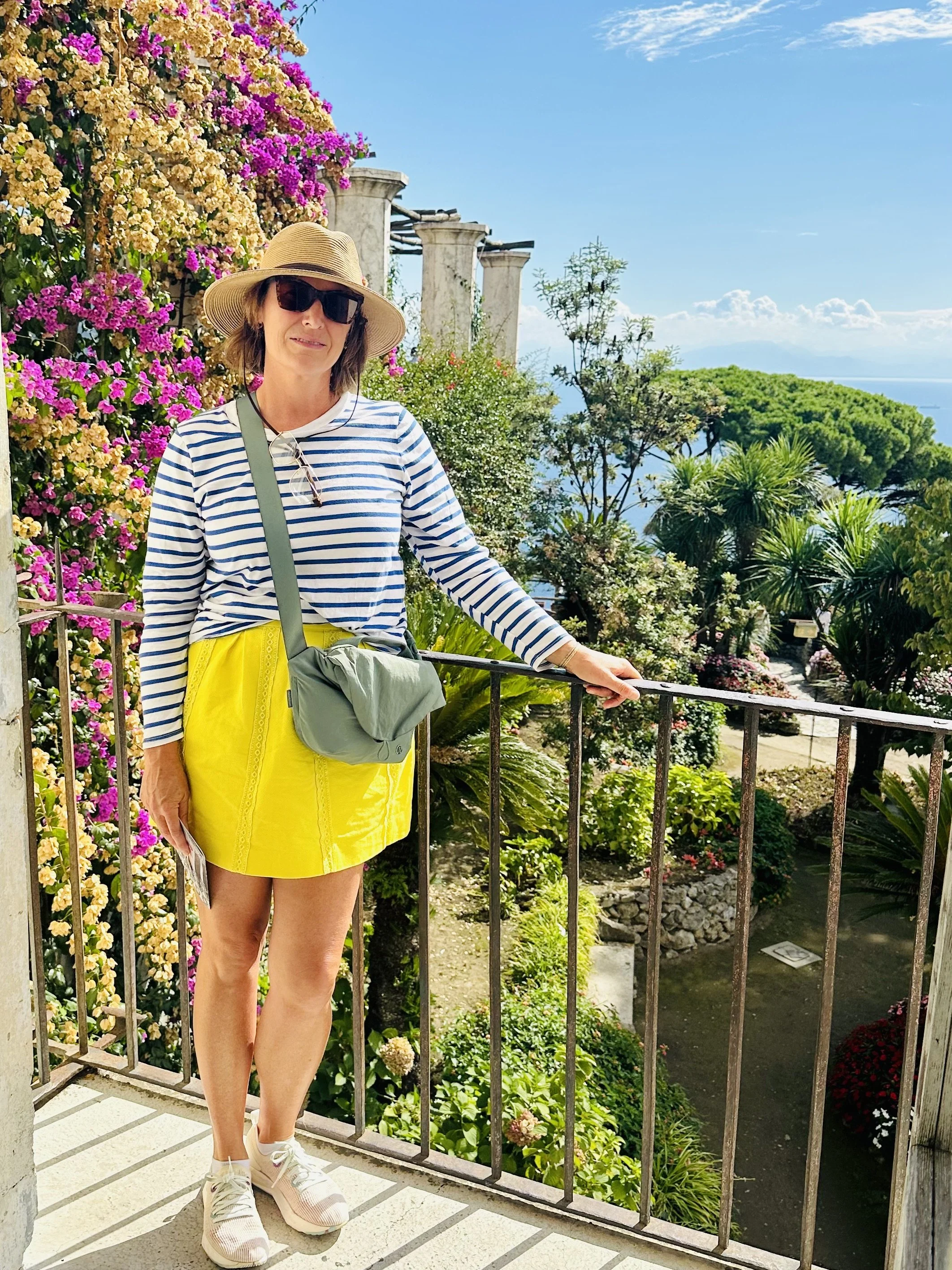 Luxury landscape designer inspired by classic Villas along the Amalfi Coast basking in bougainvillea, ancient limestone sculpture, custom wrought iron railing and capturing a classicly beautiful Italian coastal vista.