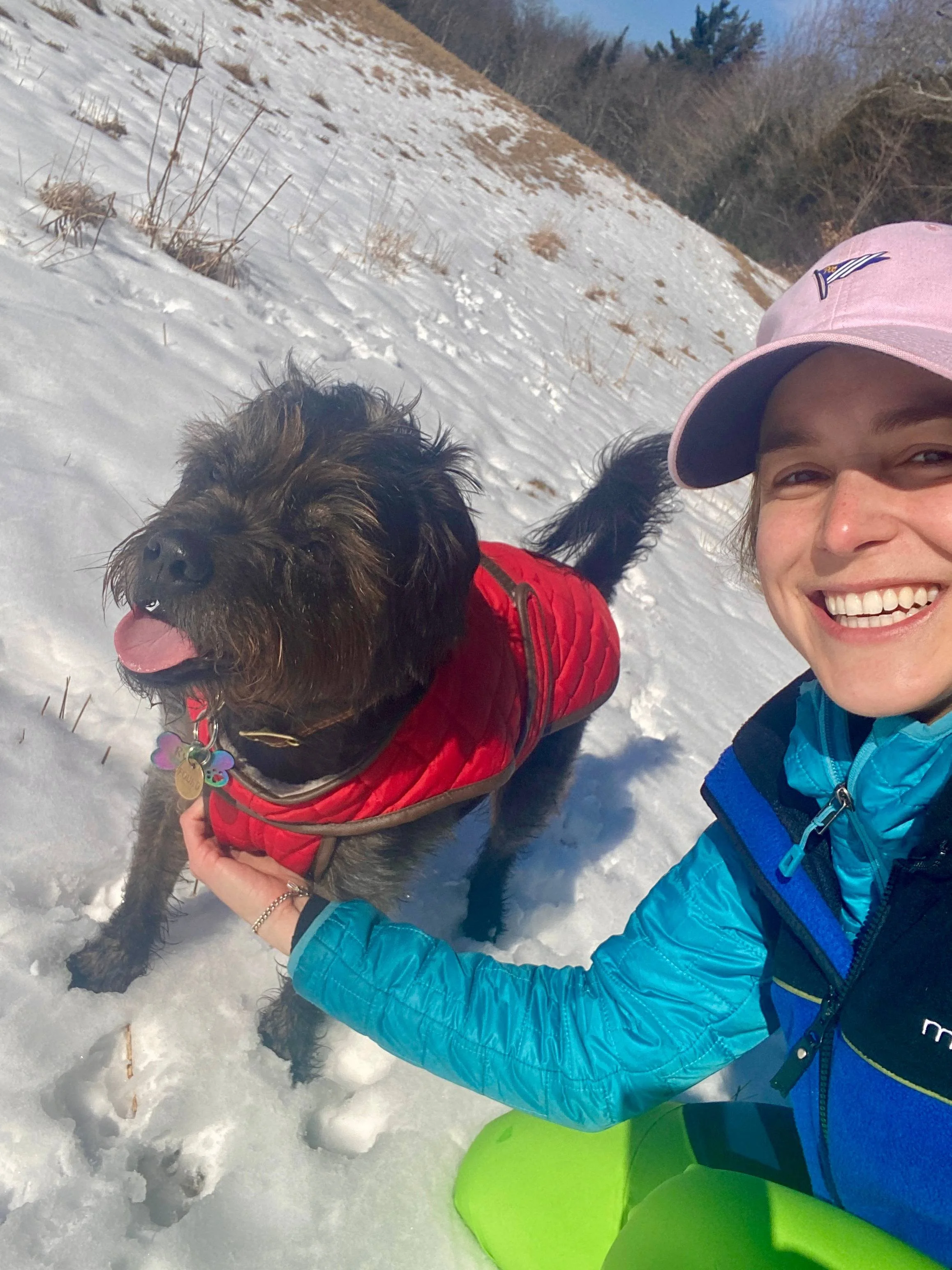 Snow selfie with red-coated dog