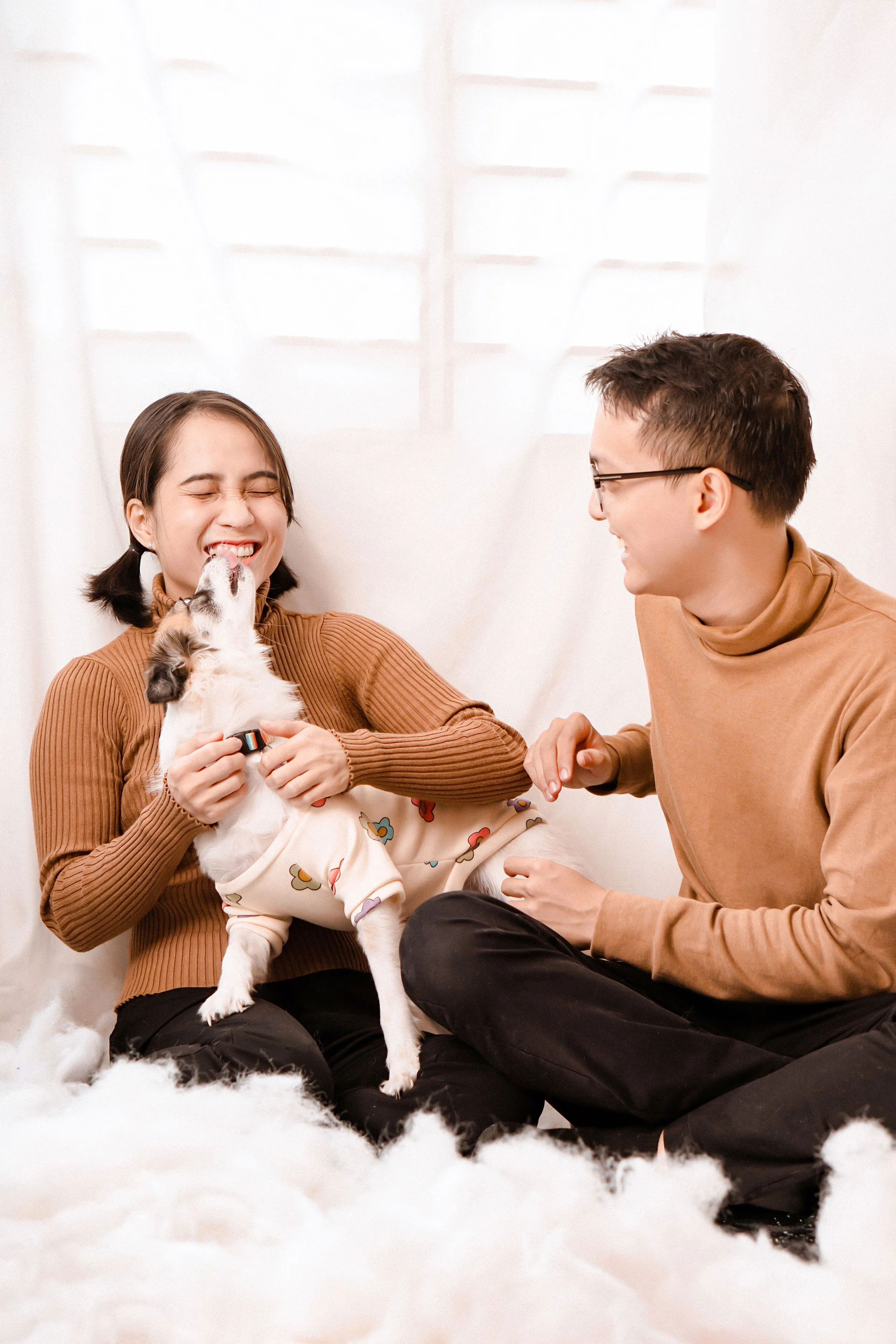 A couple plays with their small dog at home.