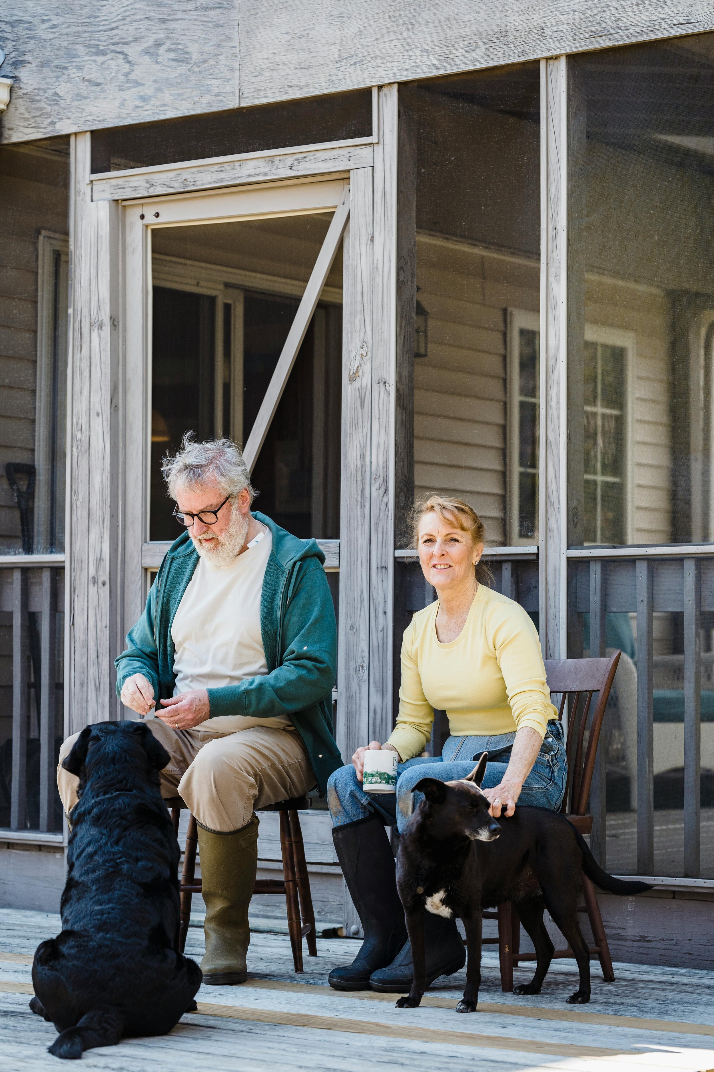 Two trusted caregivers sit with two dogs on a front porch.