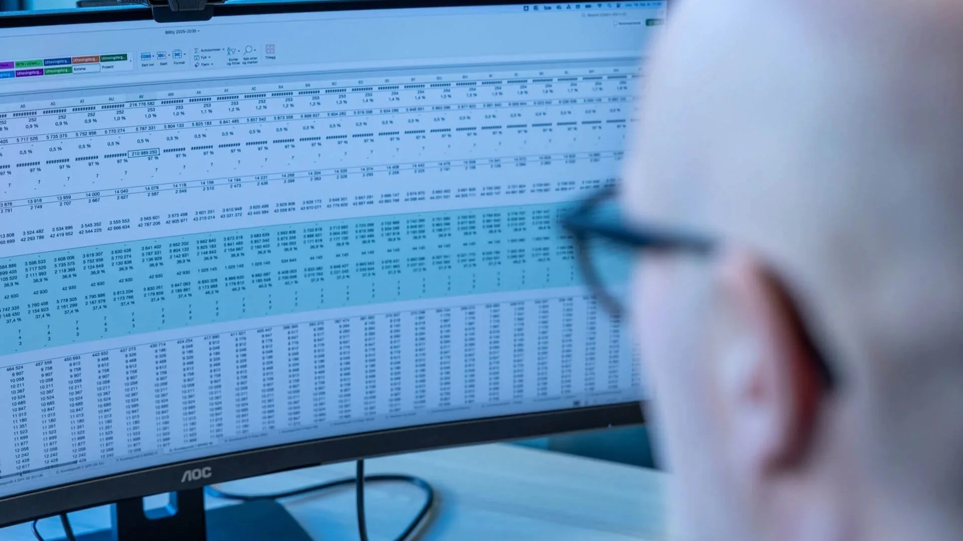 Jan Johnsen ser på en dataskjerm som viser et regneark fylt med tall og data.