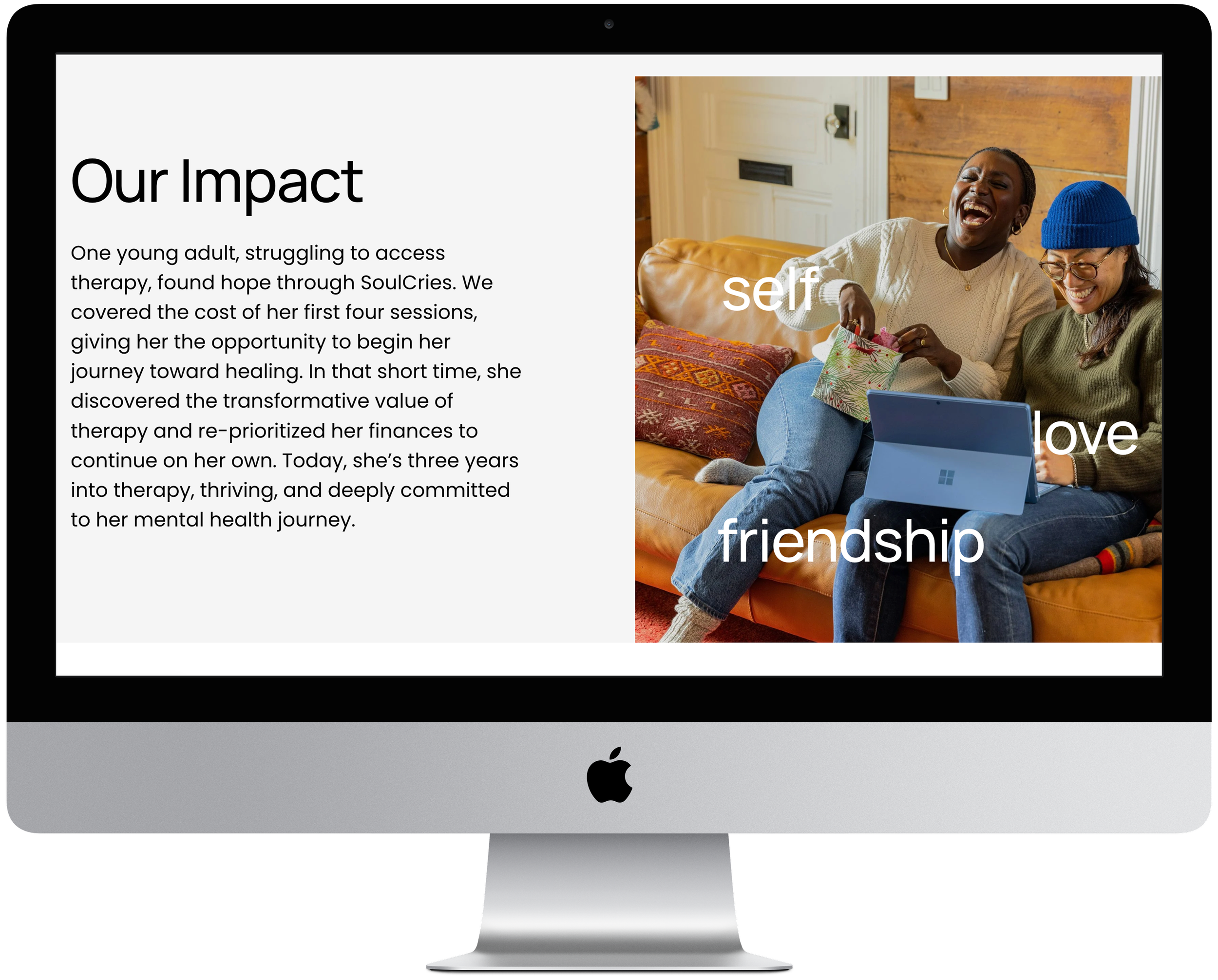 The image shows an iMac displaying a webpage with the title "Our Impact" on the left and a photo on the right of two women sitting on a couch, laughing, and engaging with a laptop. The words "selflove friendship" are overlaid on the photo.