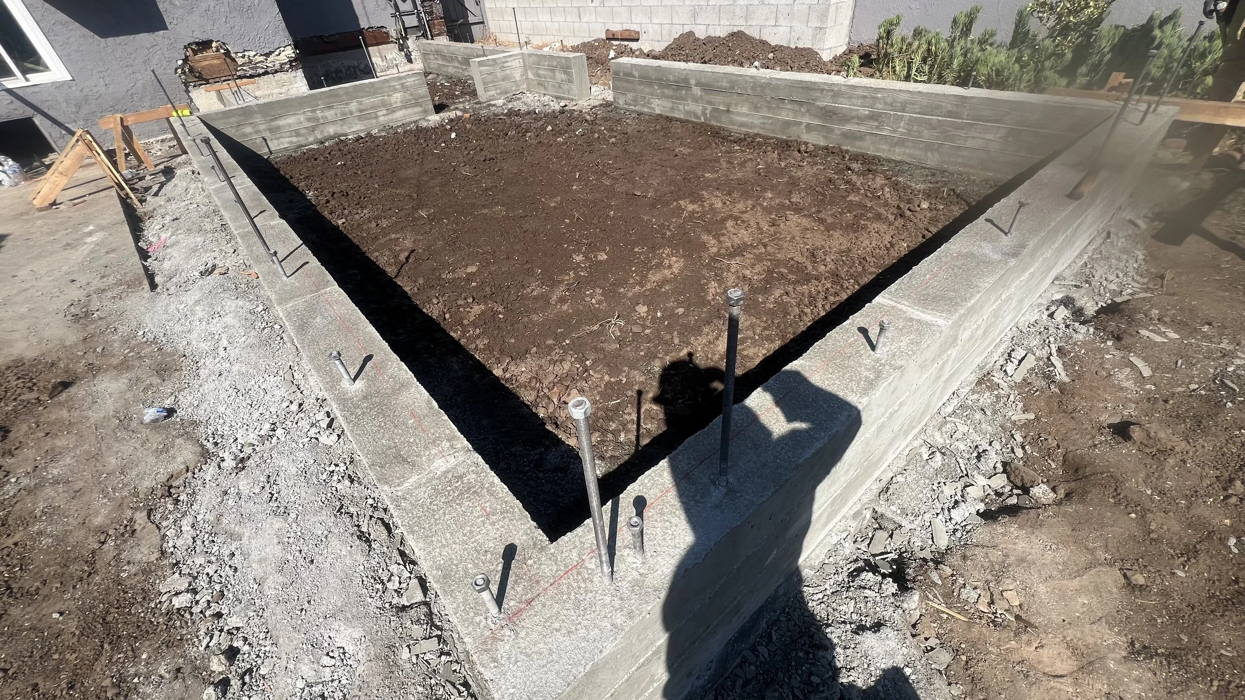 A landscape of mountains with snow-covered peaks in the background and a modern building on a grassy hill in the foreground.