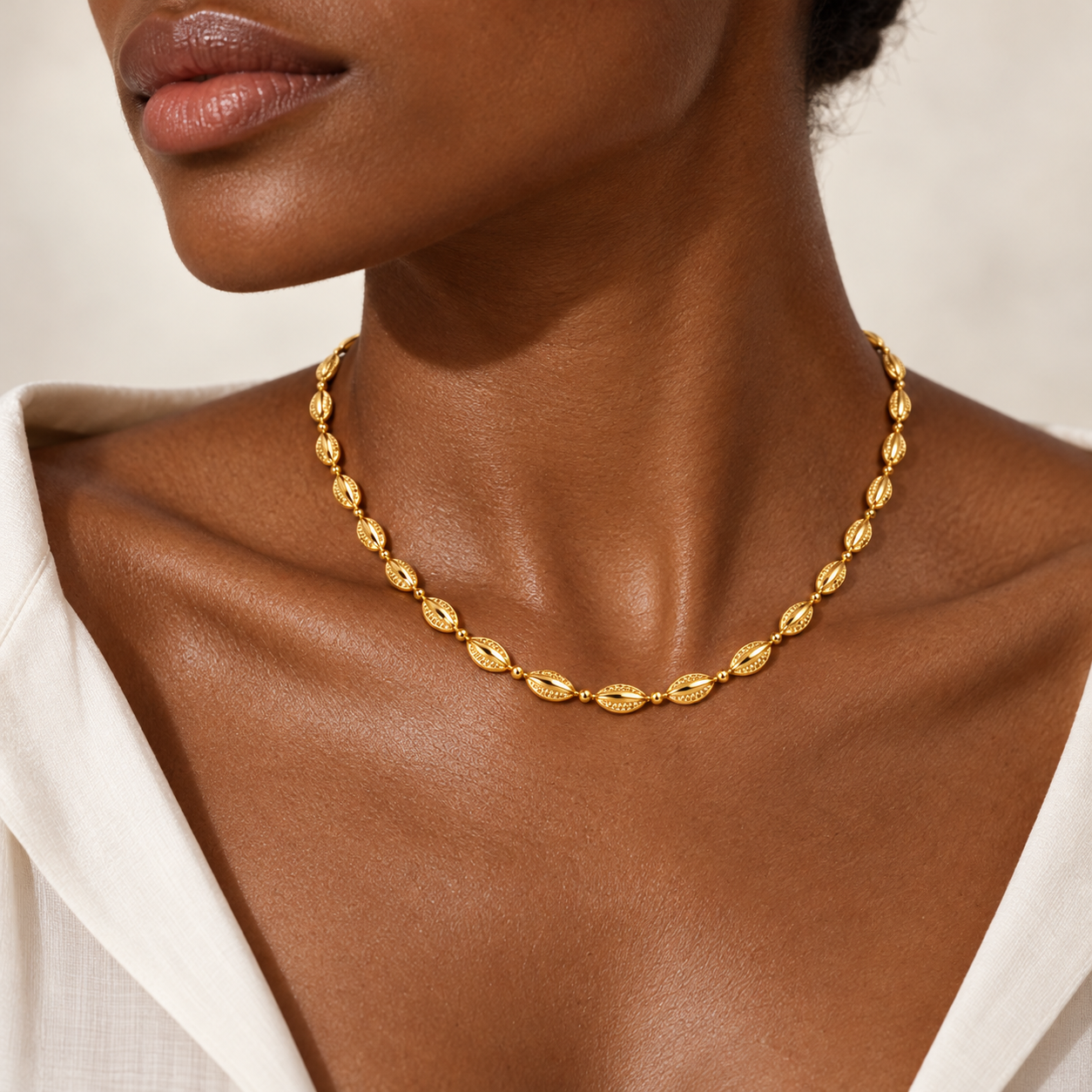 Golden Cowrie Necklace in yellow gold worn at the collarbone, shown as a model styling concept.