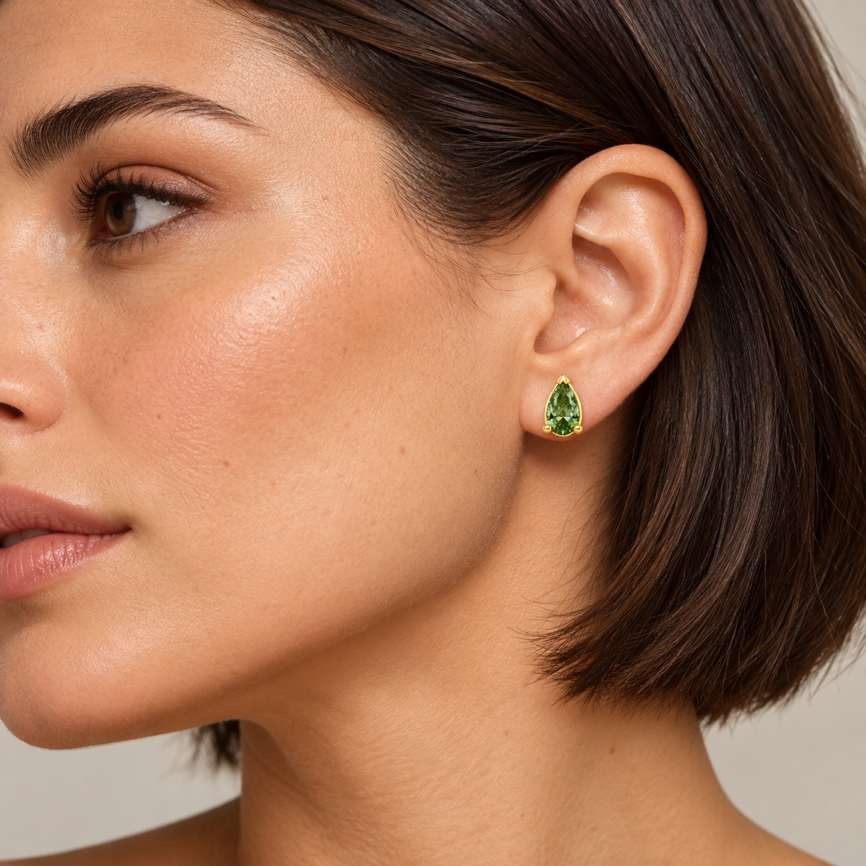 Styling concept of an adult model wearing a yellow-color Verdant Goutte pear-shaped green-stone stud.