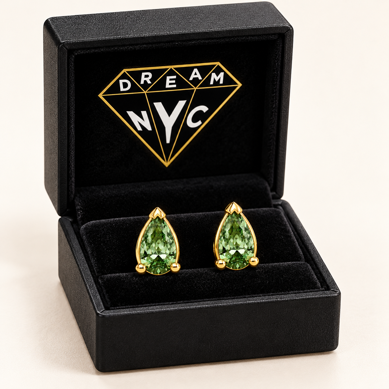 Packaging concept showing Verdant Goutte pear-shaped green-stone studs in a black DREAM NYC box with the diamond logo inside the lid.