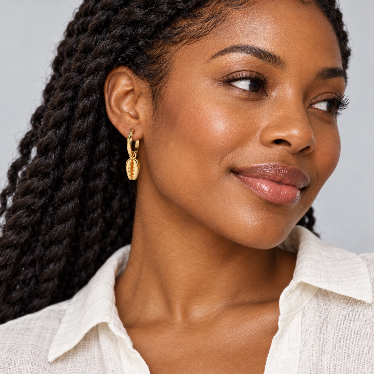 Tide Cowrie Hoops in yellow gold worn on a model, illustrative styling concept
