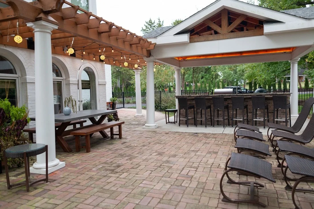 A gorgeous outdoor kitchen with a custom gazebo and landscape lighting using recycled clay pavers in Westwood