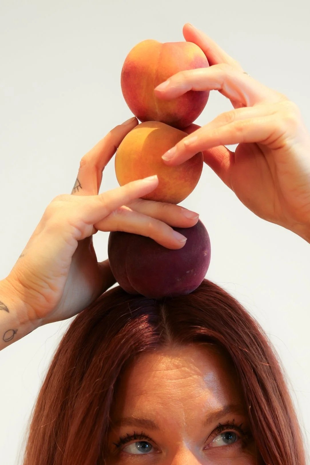 Alison Thacker, Founder of TheCheekyClean Lifestyle Detox Course, stacks three peaches on top of her head.