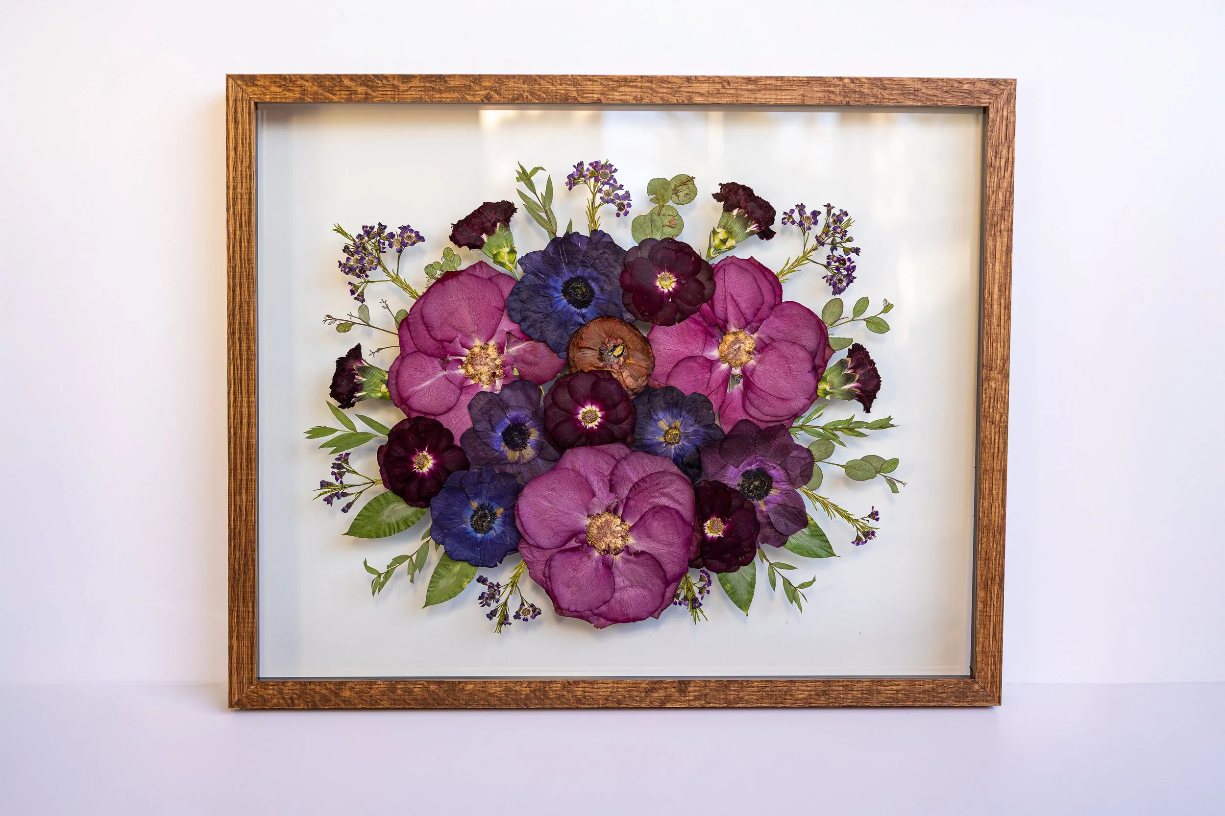 Pink, purple and blue pressed flowers fill a frame.