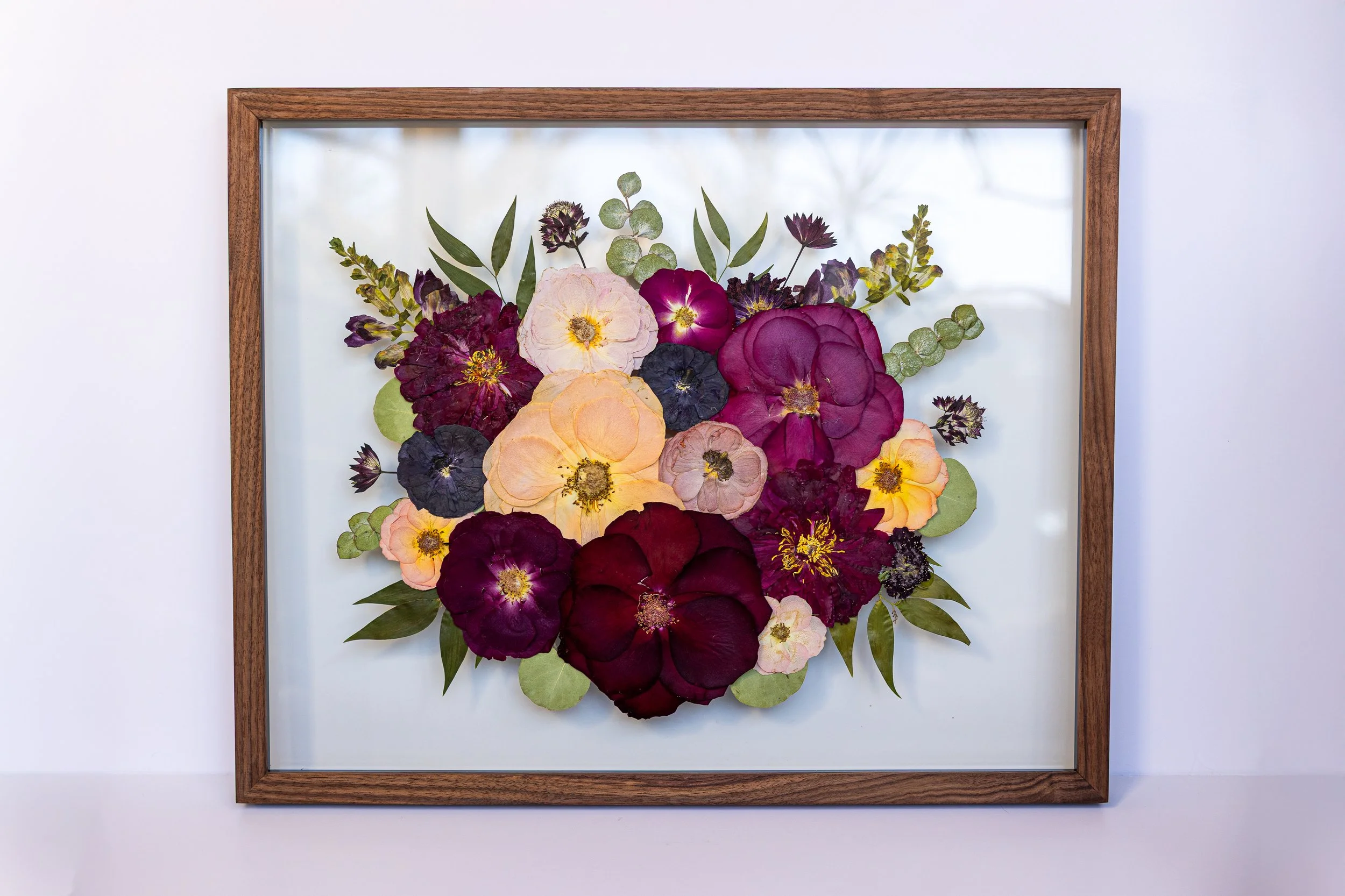 Pink and purple pressed flowers fill a frame.
