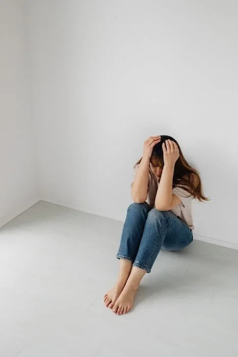Girl sitting on the ground with head in hands