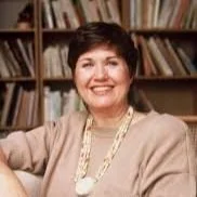 Smiling individual sitting in front of a bookshelf