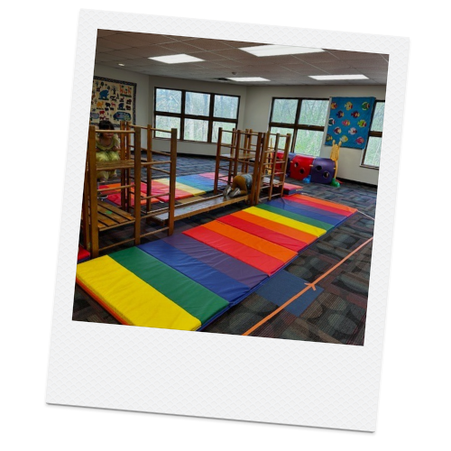 Indoor children's playroom with mat climbing structure and colorful rainbow mats.