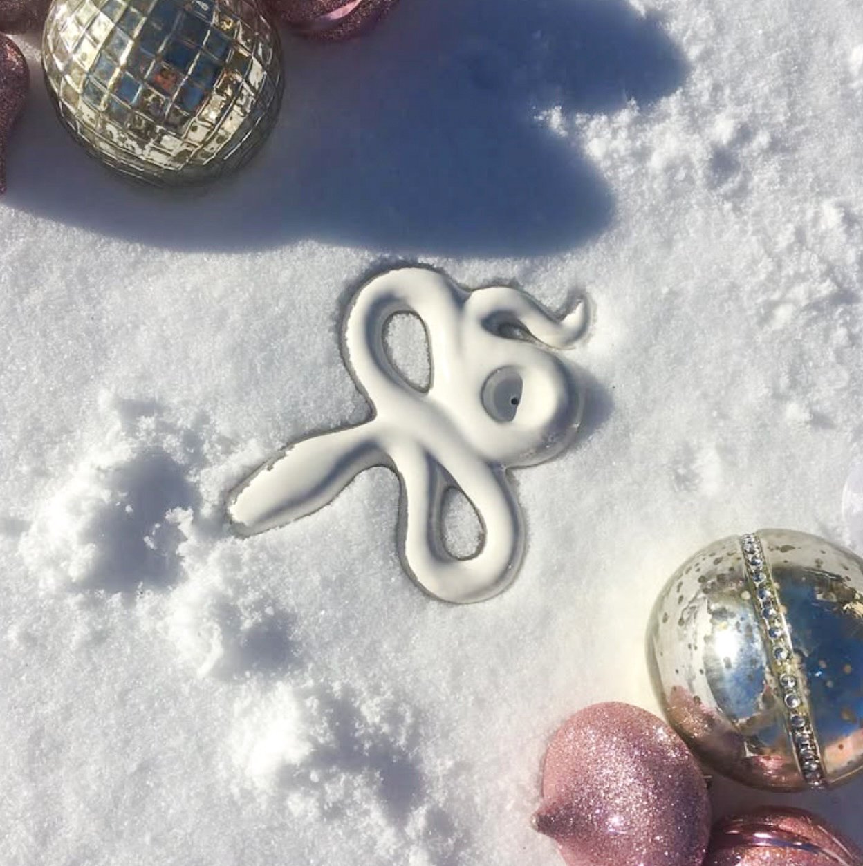 Snake-shaped meringue on snow with reflective and pink ornaments