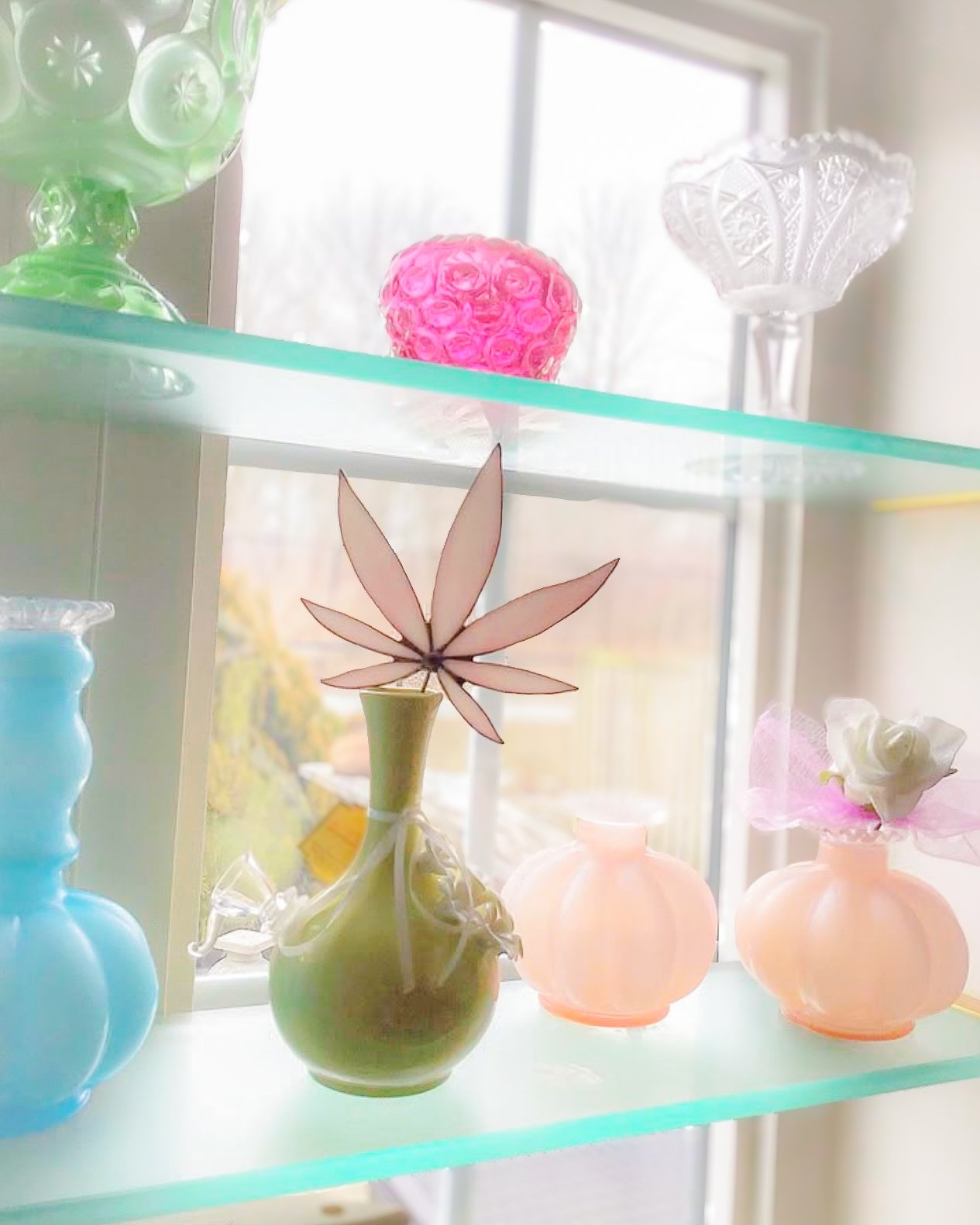 Glass vases on a shelf with decorative designs, including green, pink, and blue colors.