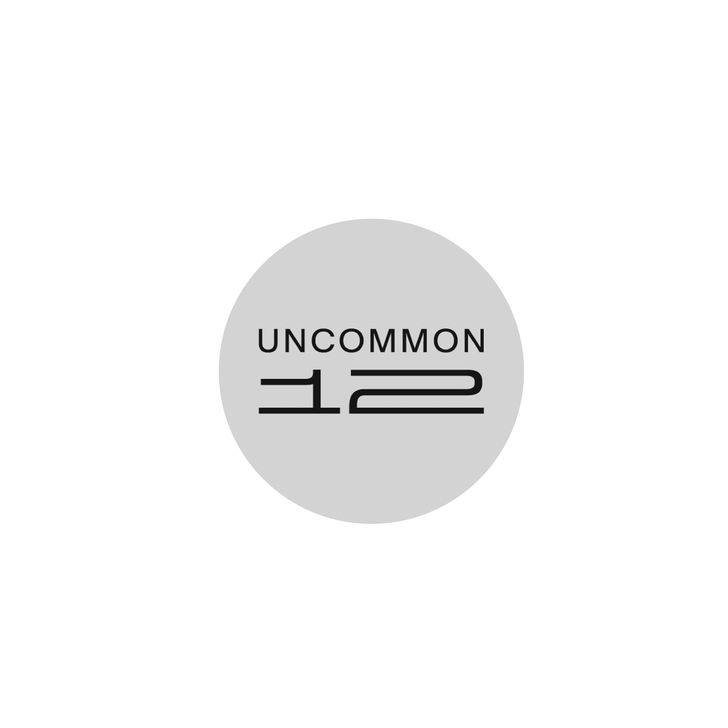 A logo for the Uncommon 12 project, featuring a gray circle with the words 'Uncommon 12' inside and a large black arrow pointing upward.