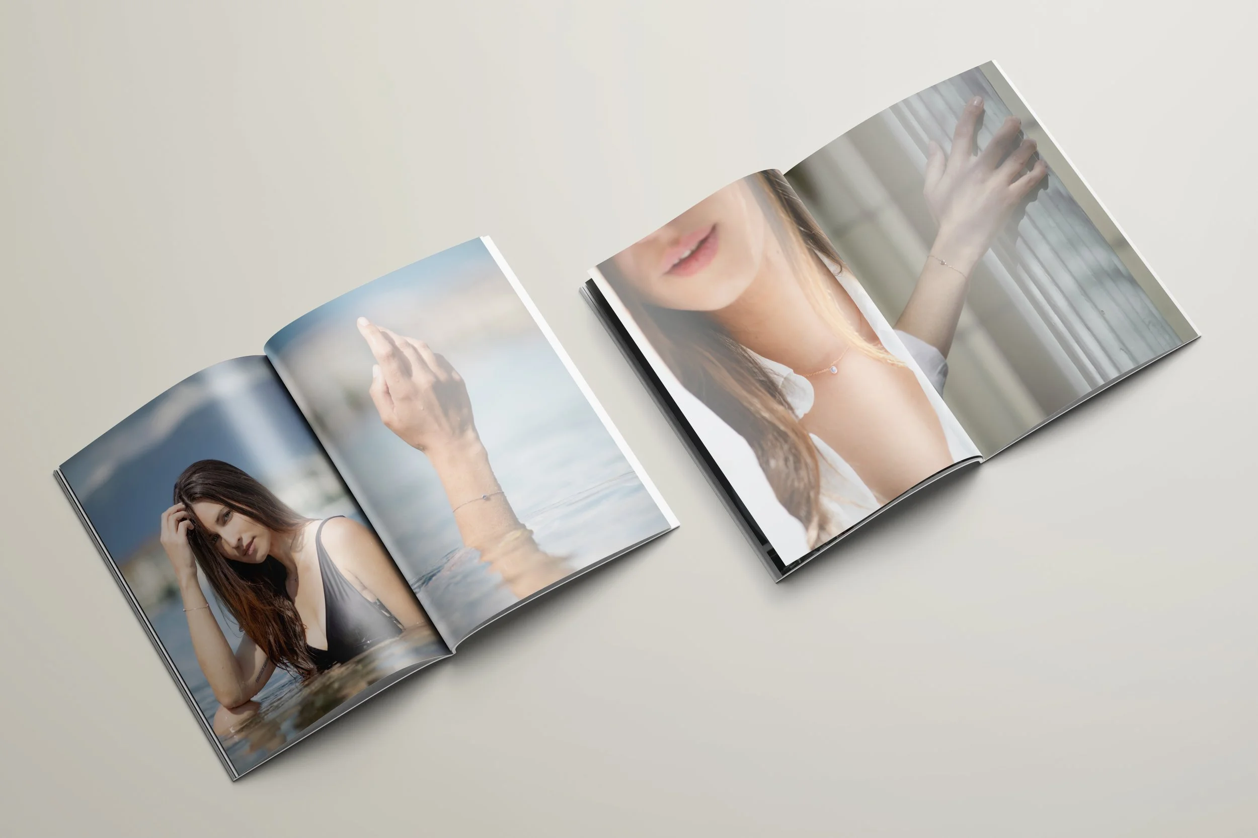 Open magazines on a table, featuring images of a woman in a swimsuit and jewelry.