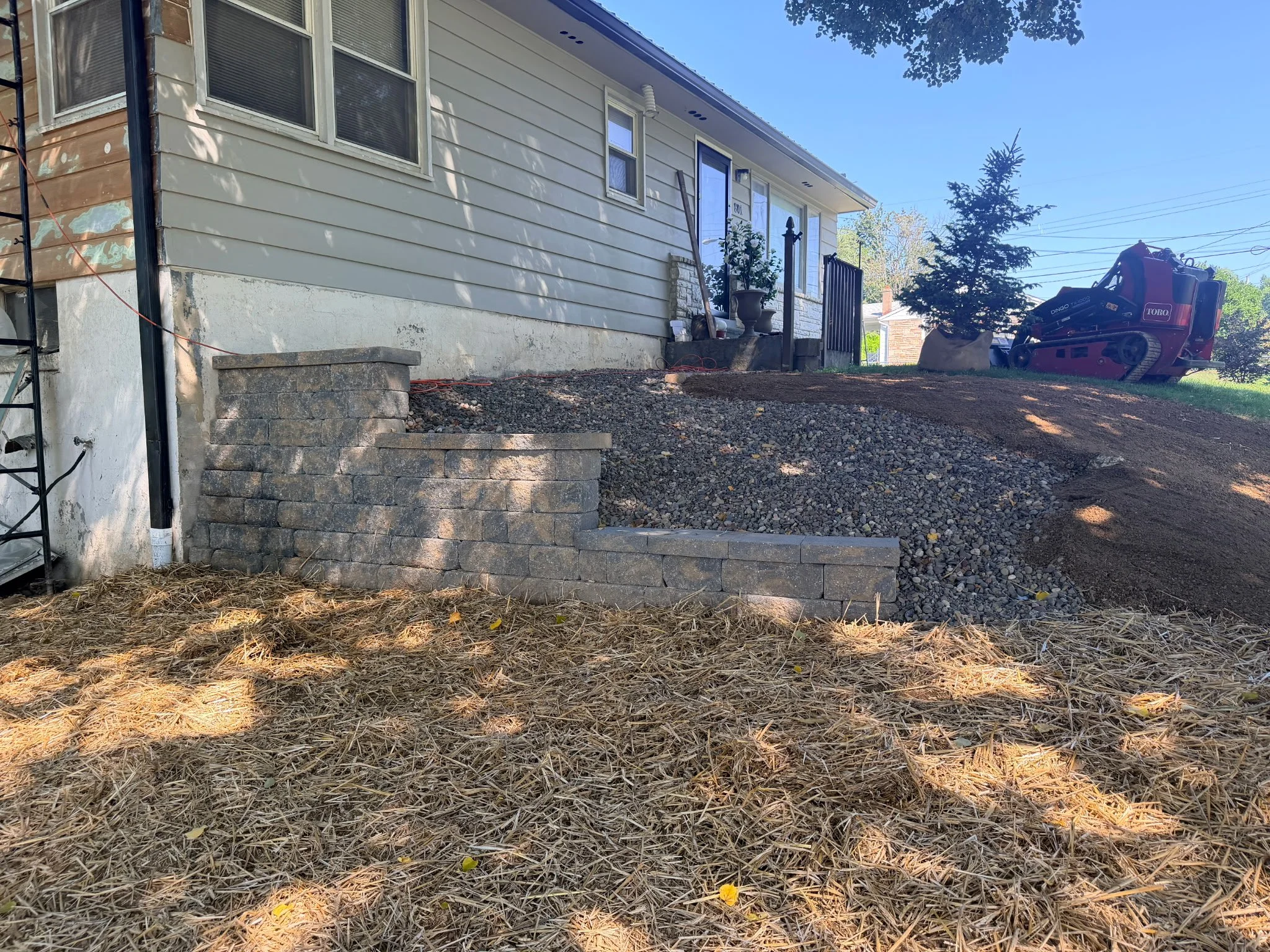 Finished stone retaining wall with built-in steps along a home's foundation in Harrisburg, PA