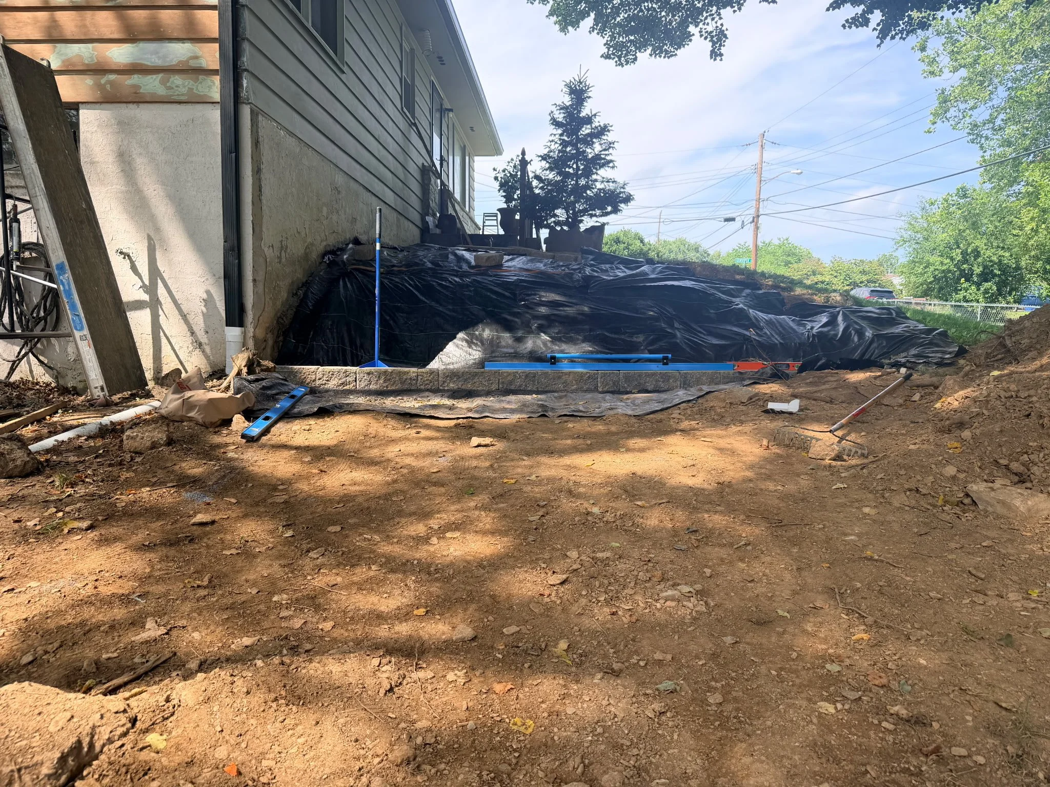Sloped, eroding yard before retaining wall installation, with base course being leveled