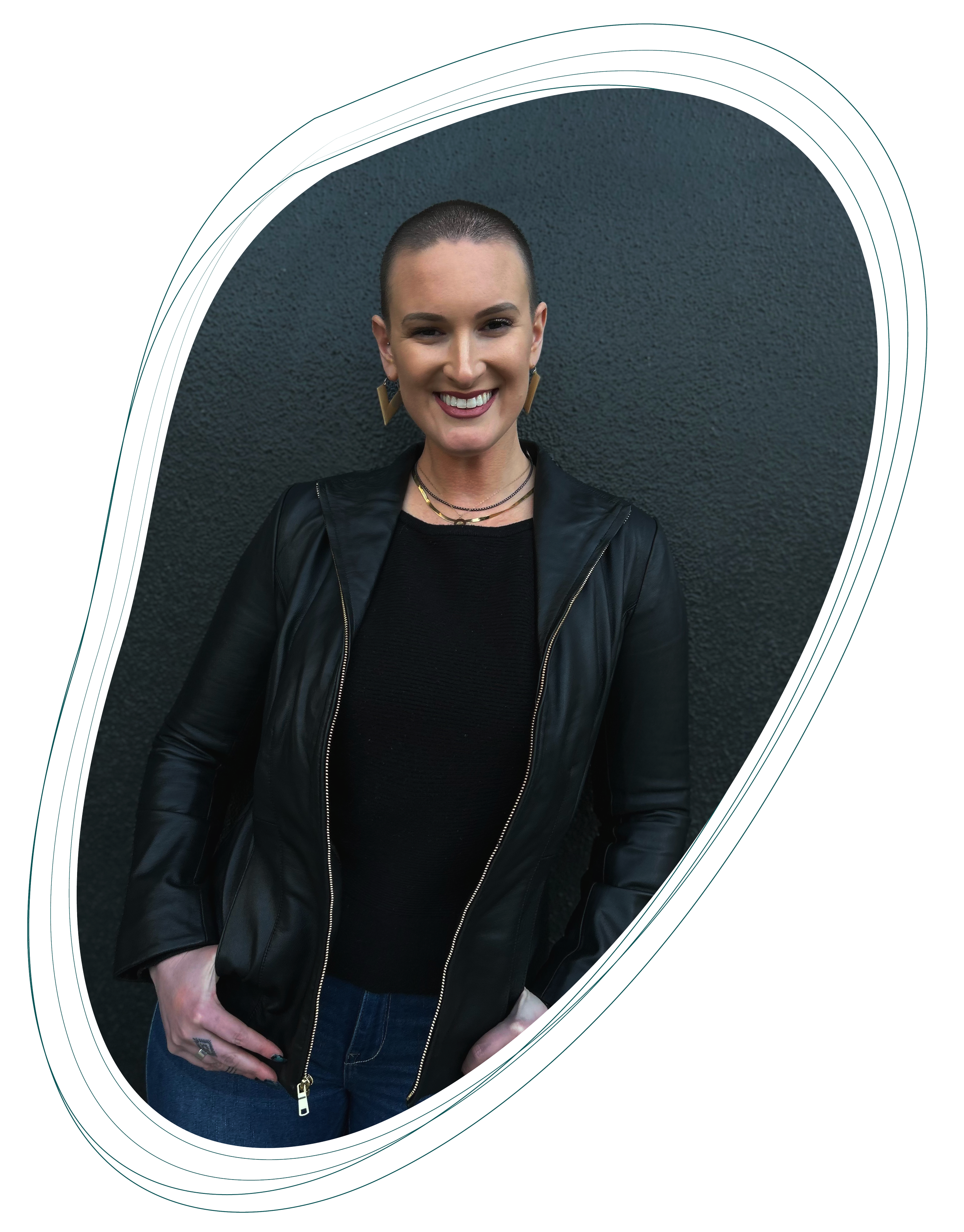 Austin trauma therapist, Arielle Sokoll-Ward, smiling and standing against a dark textured wall, wearing a black leather jacket and jeans, framed by an abstract multicolored oval outline.