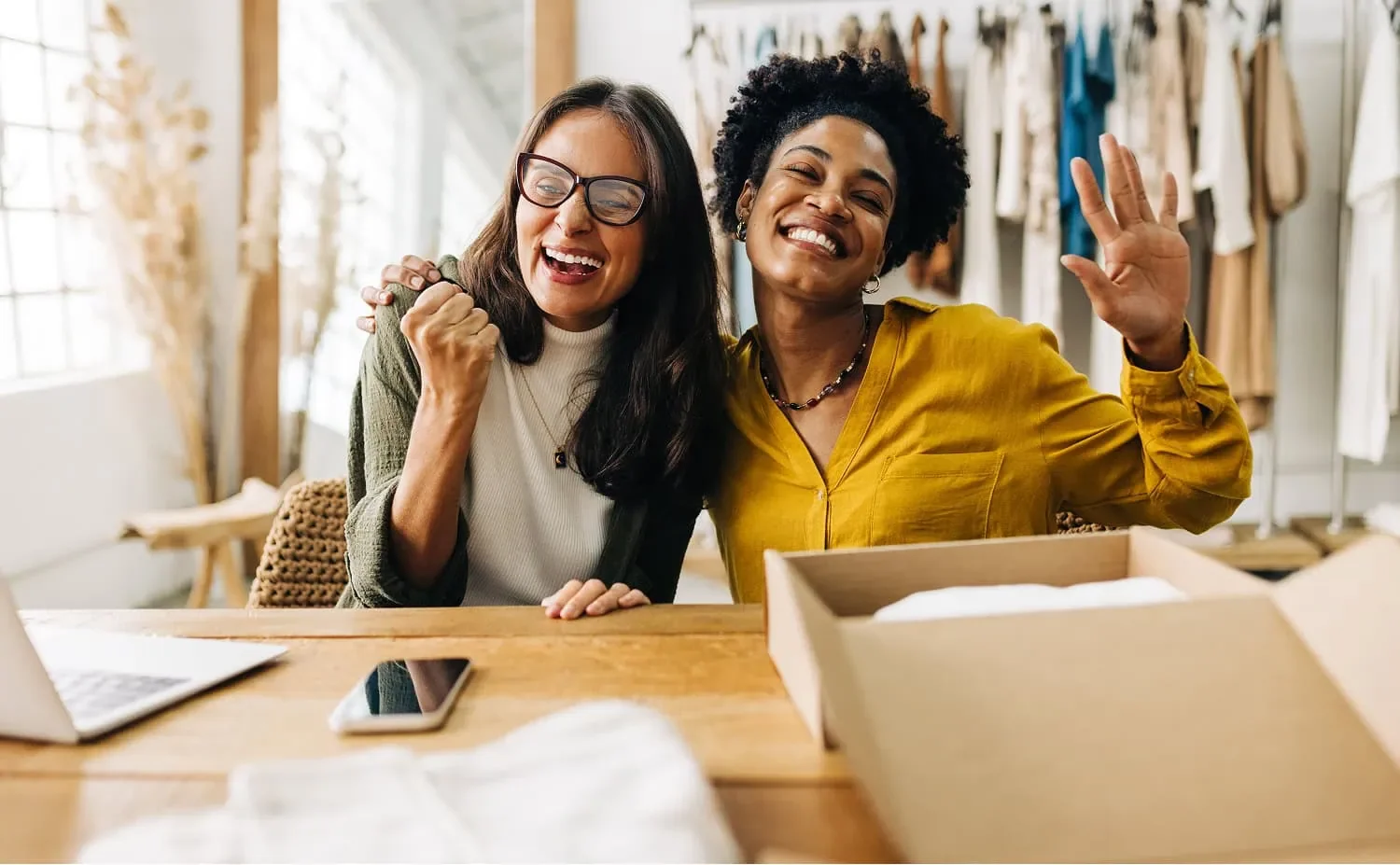 two women entrepeneurs laughing together while supporting each other through financial challenges