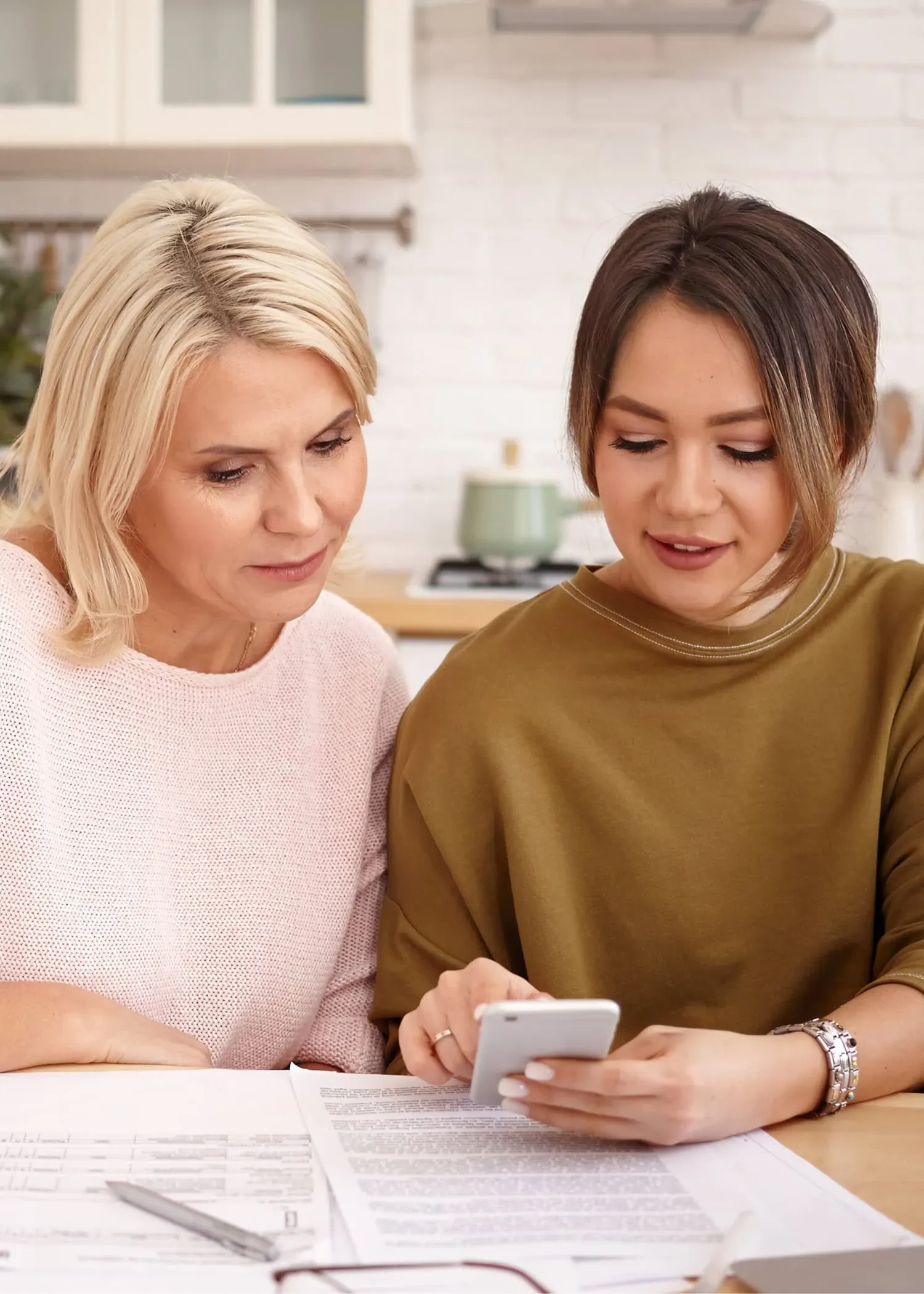 two women reviewing documents and cellphone with business financing team in Alberta