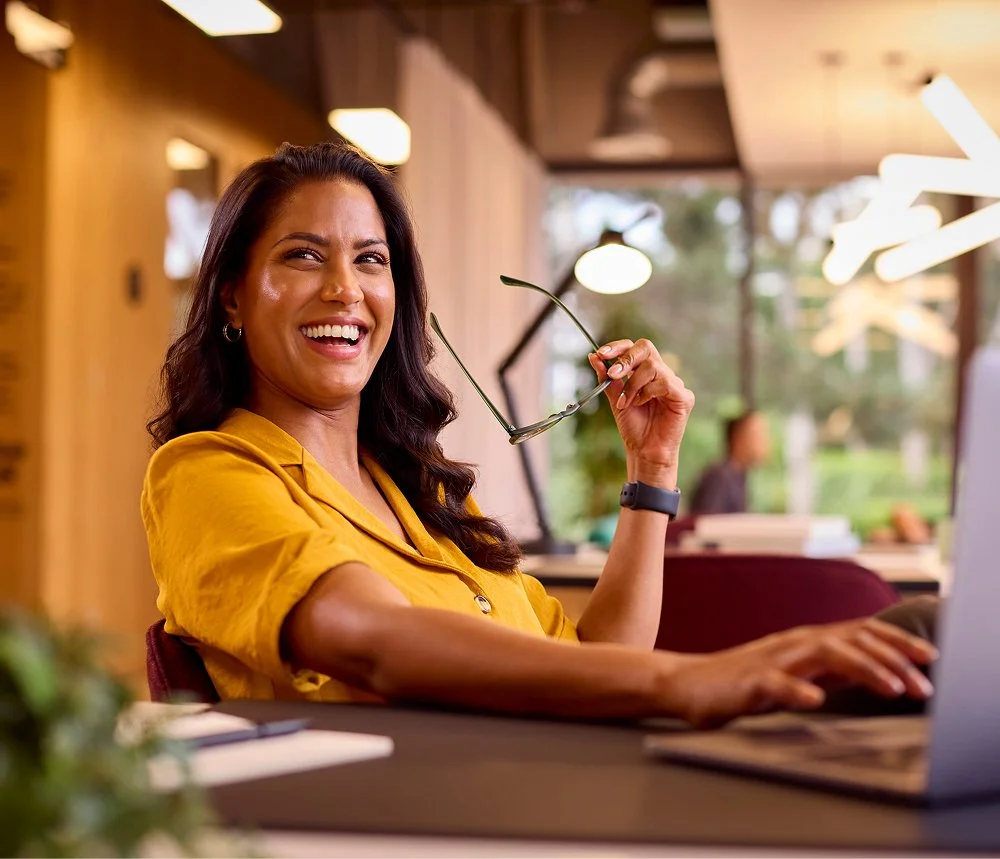 woman laughing next to laptop during business conversation