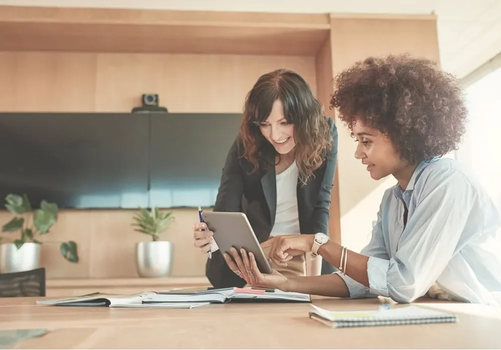 two women discussing business plan together on laptop