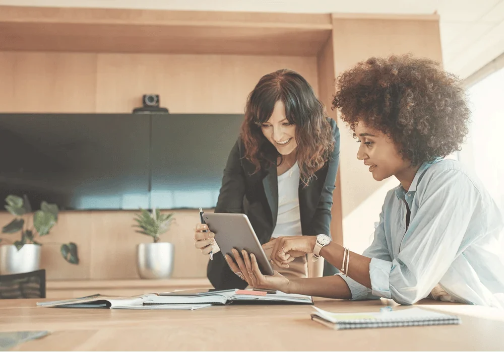 two women collaborating on tablet receiving expert business guidance