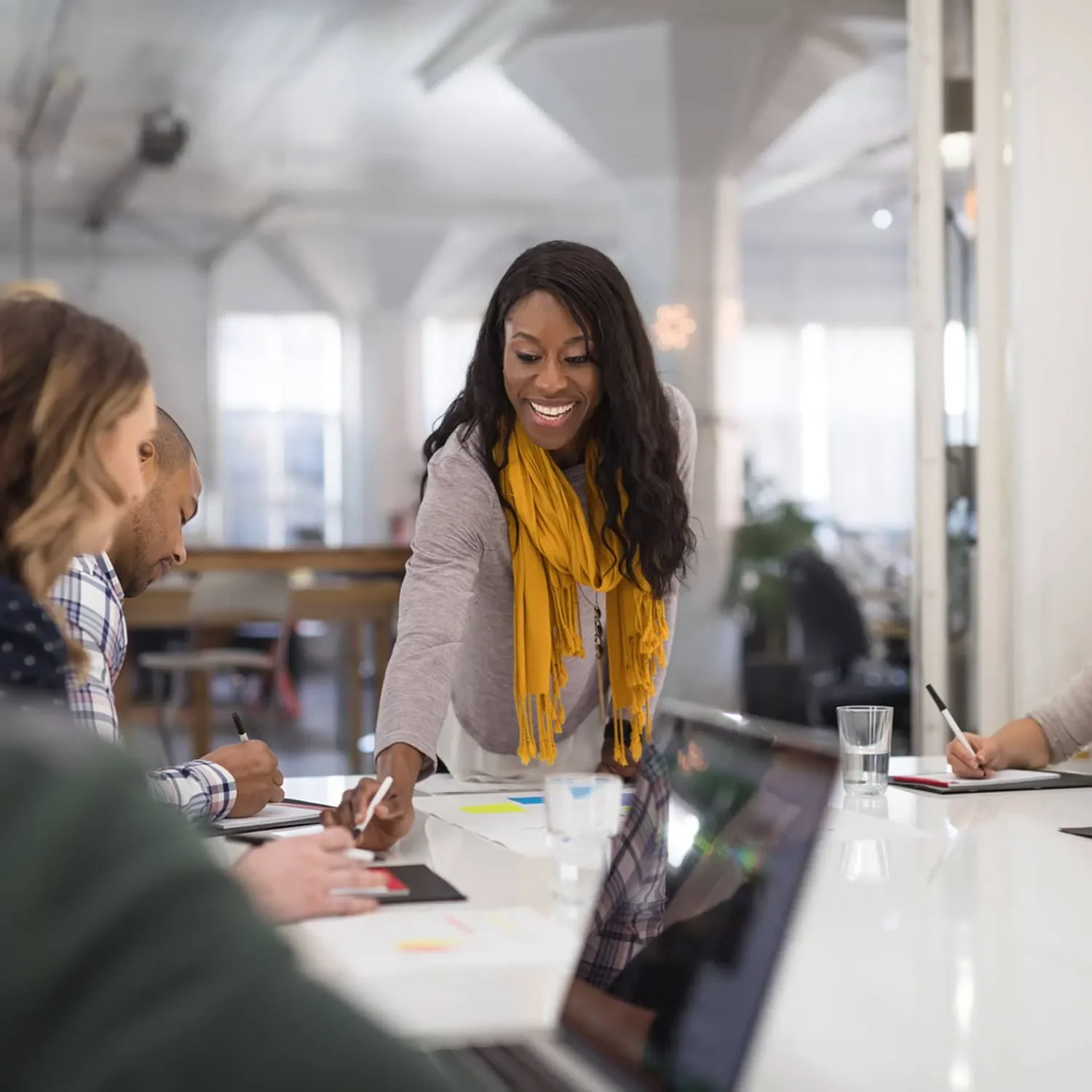 Woman smiling during meeting while pointing something out to colleague