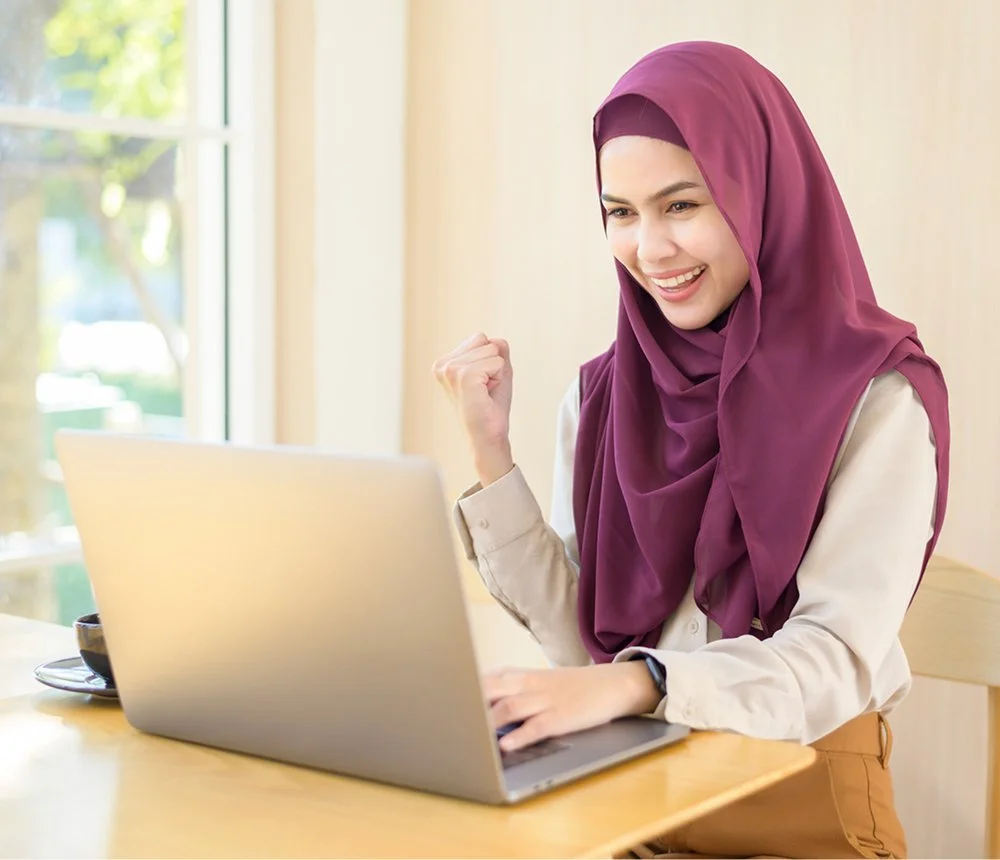 woman celebrating success beside laptop after finding business support resources
