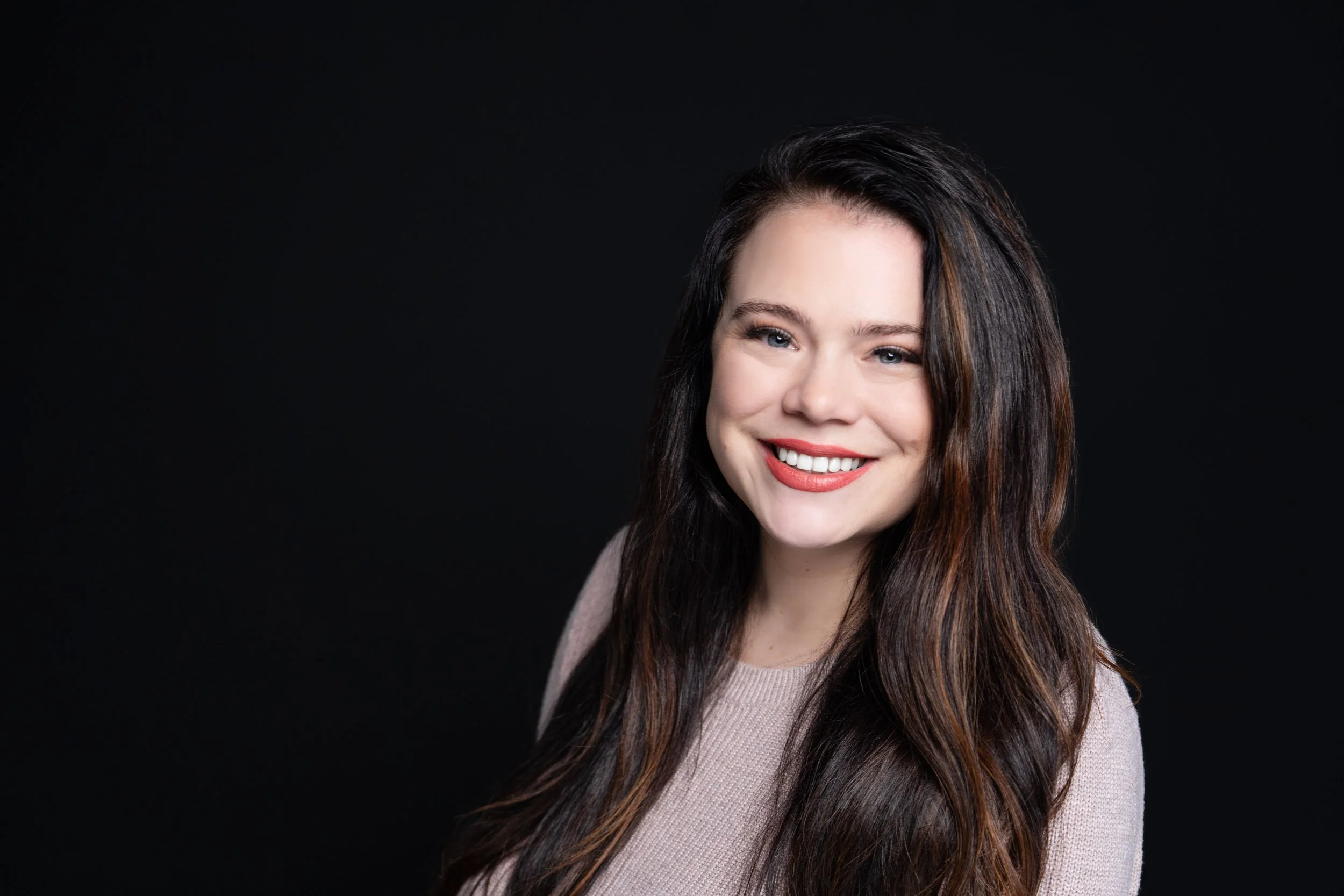 headshot of a brunette woman on a black background by portrait playdate