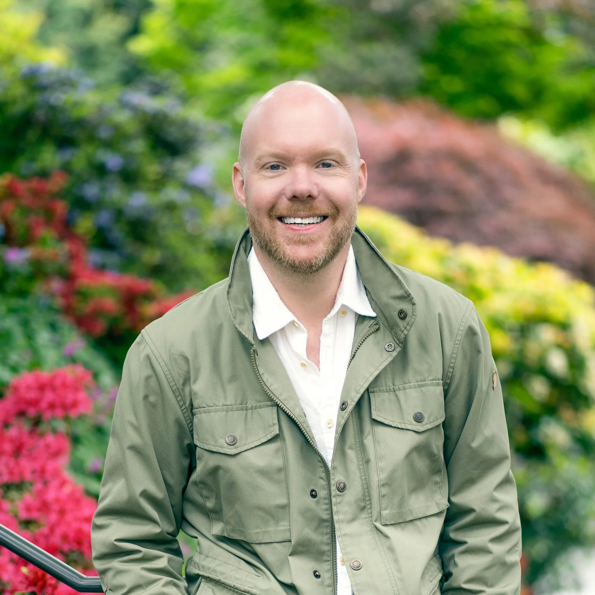 headshot of a man in a green jacket against colorful foliage in the background - portrait playdate