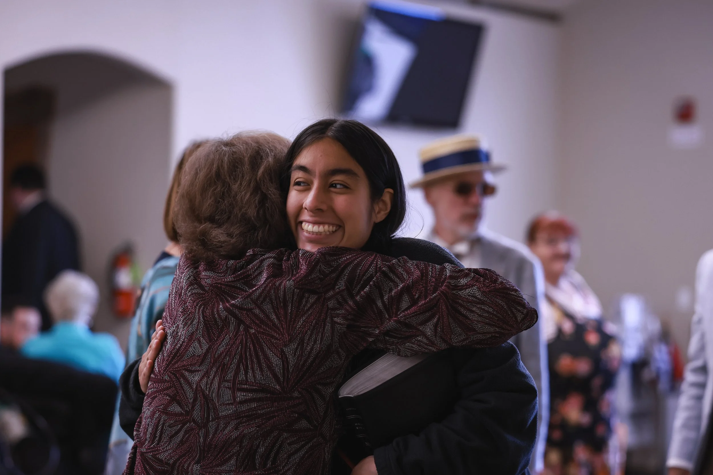 Greeting Luz and Pastor Sharon Hug Foyer.JPG