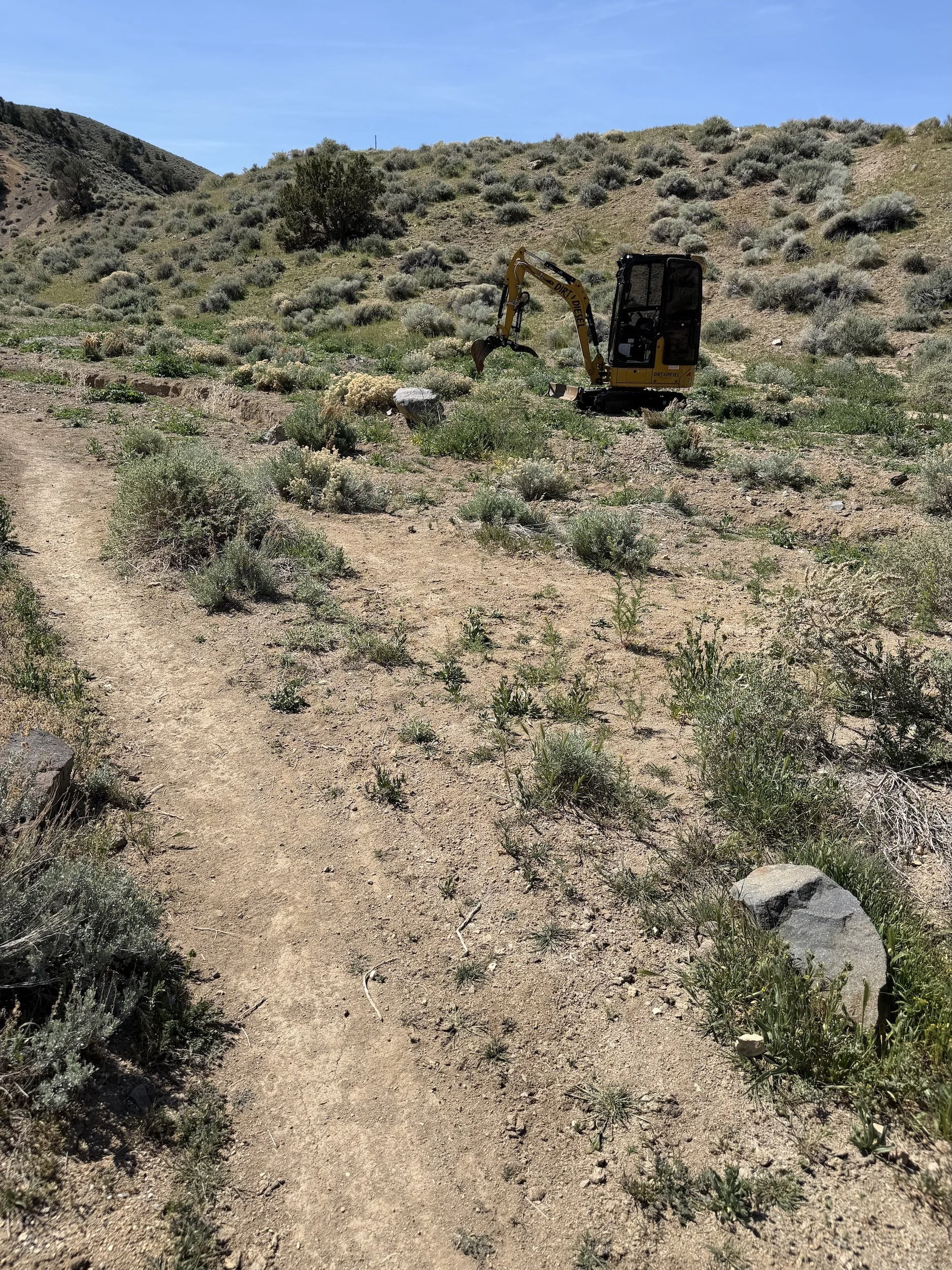  Excavator building a natural surface trail across a sagebrush flat in 