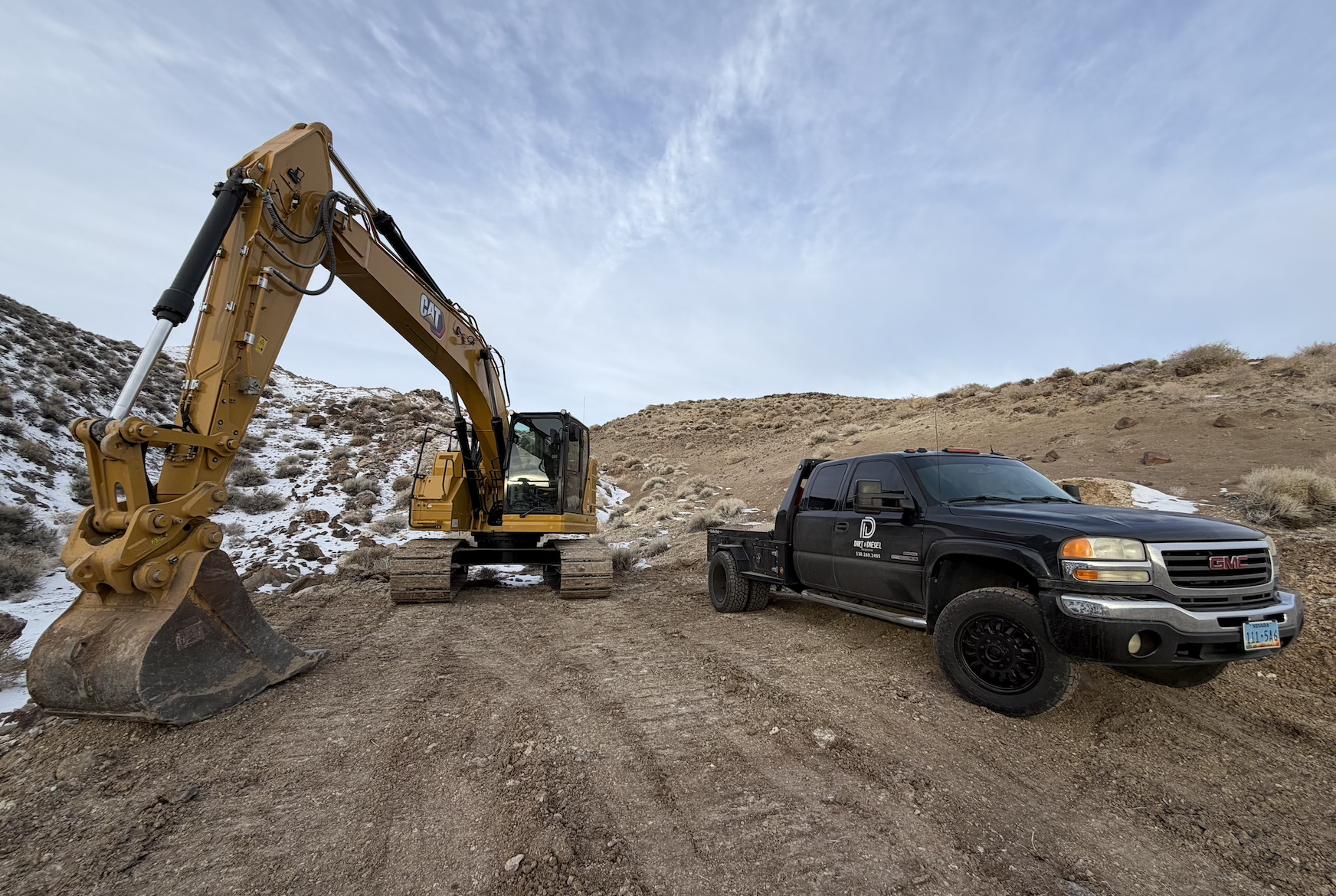 Yellow excavator and Dirt & Diesel truck on a dirt access road in Northern Nevada
