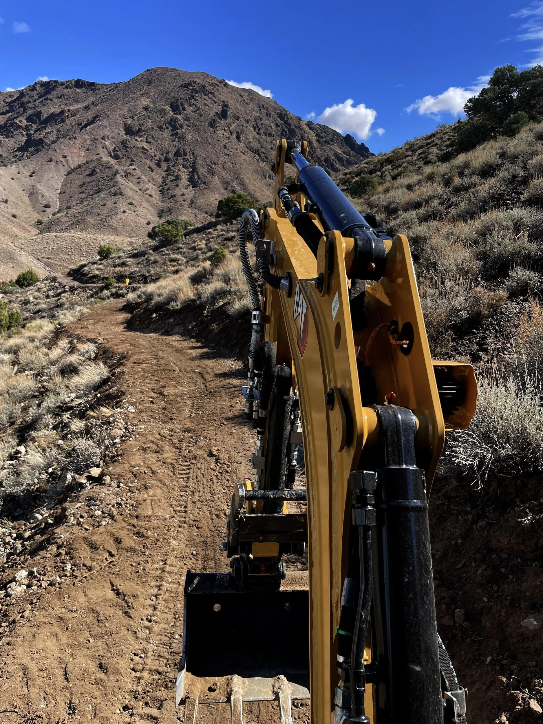 Excavator building a natural surface trail on a sagebrush hillside