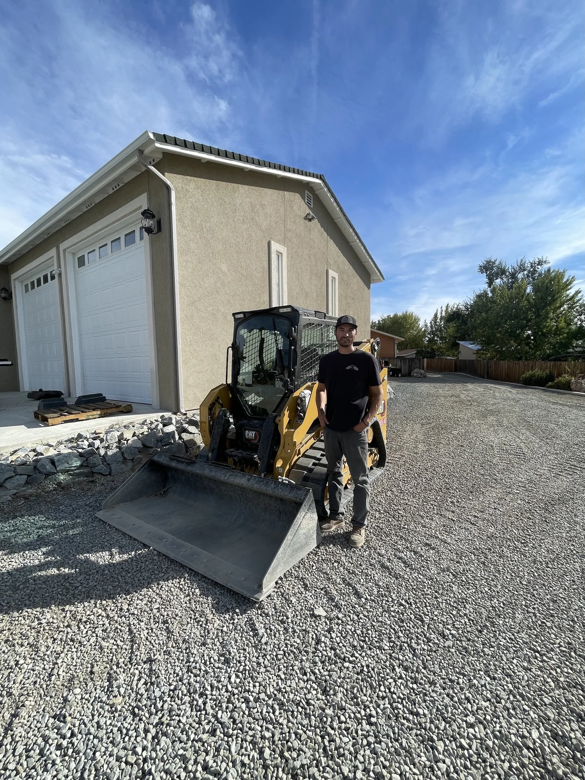 Track loader and crew member in front of a shop building