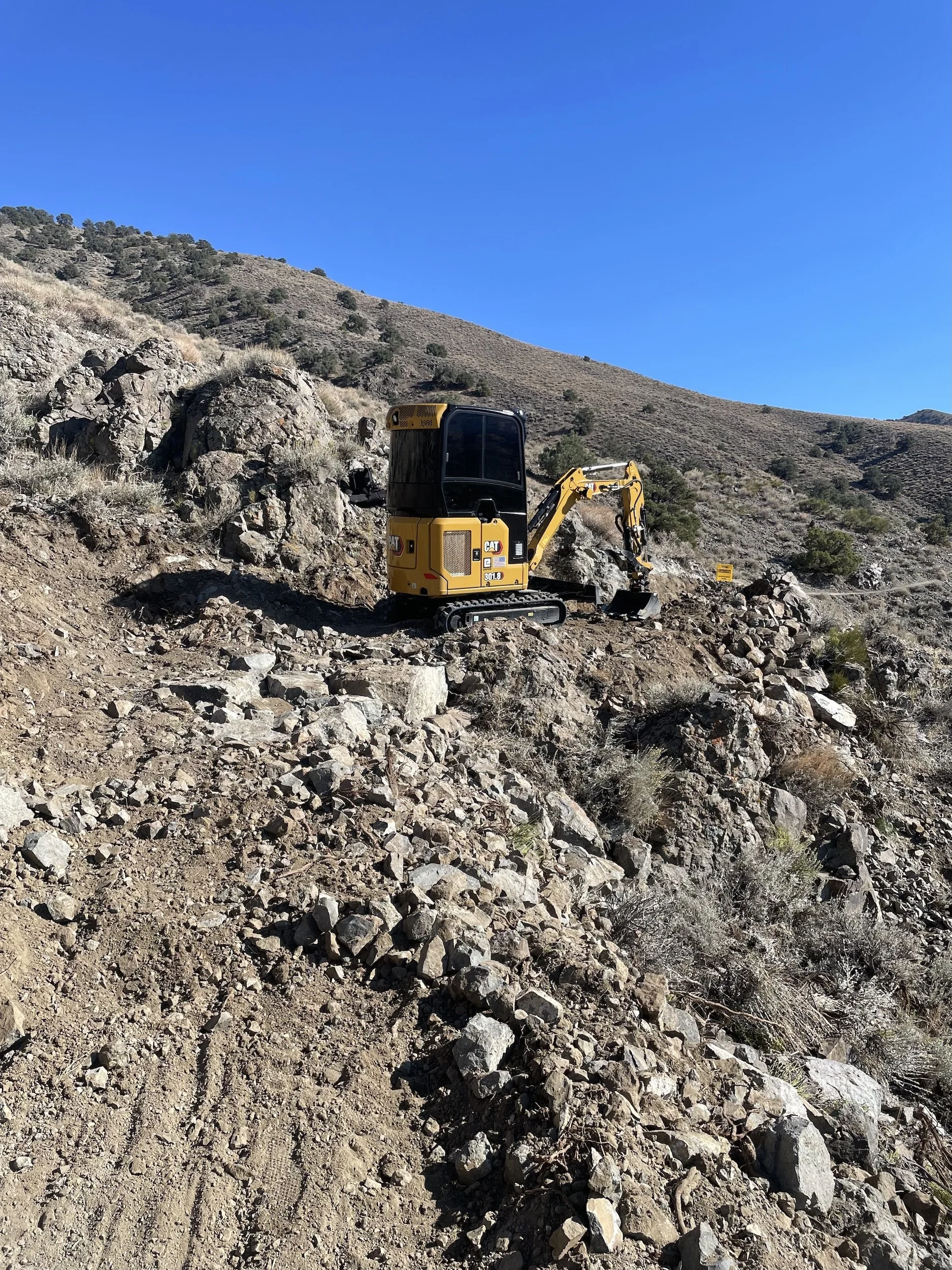 Excavator working on a steep rocky hillside in Northern Nevada