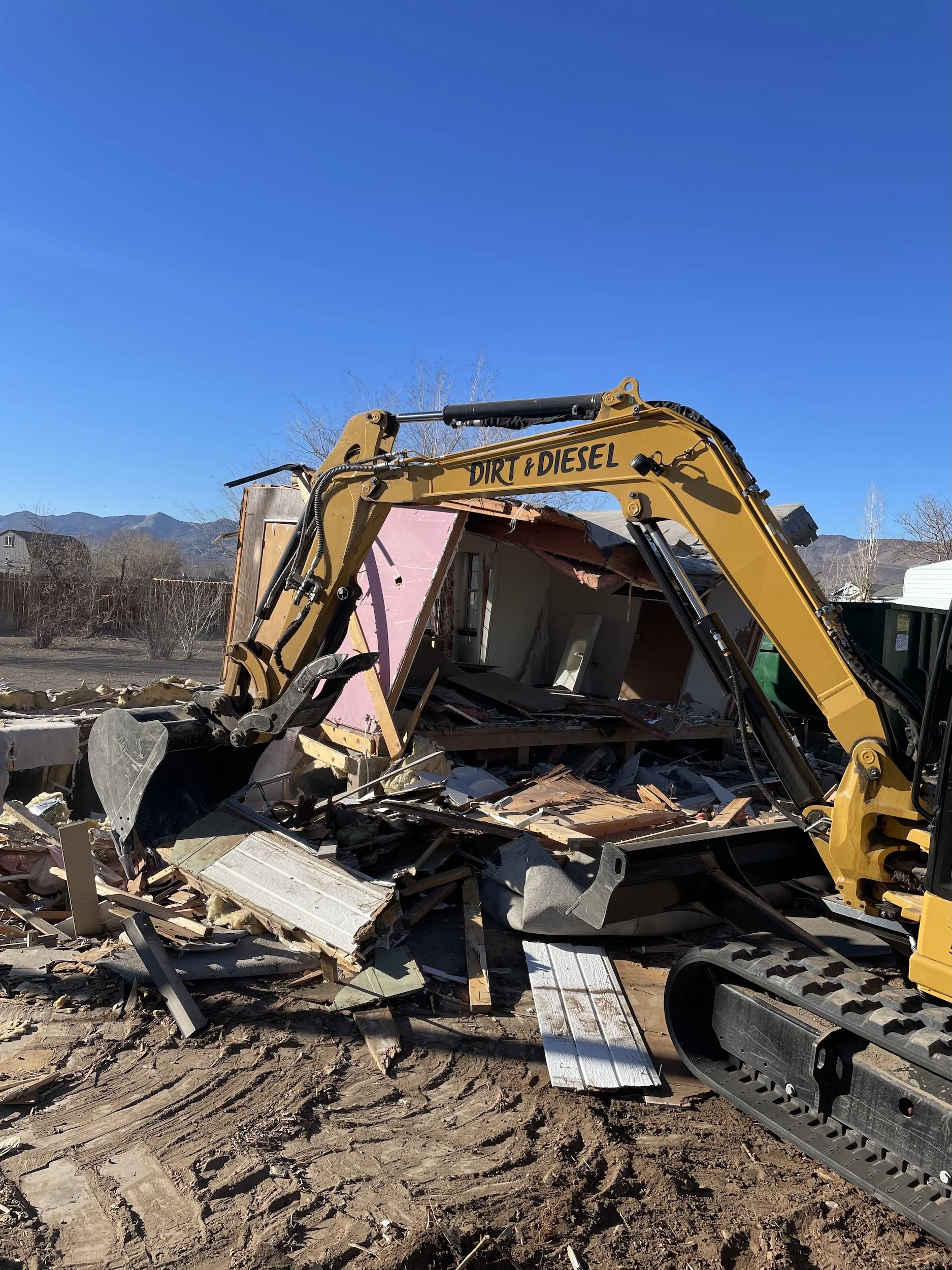 Excavator tearing into a pile of demolition debris from a structure near Carson City