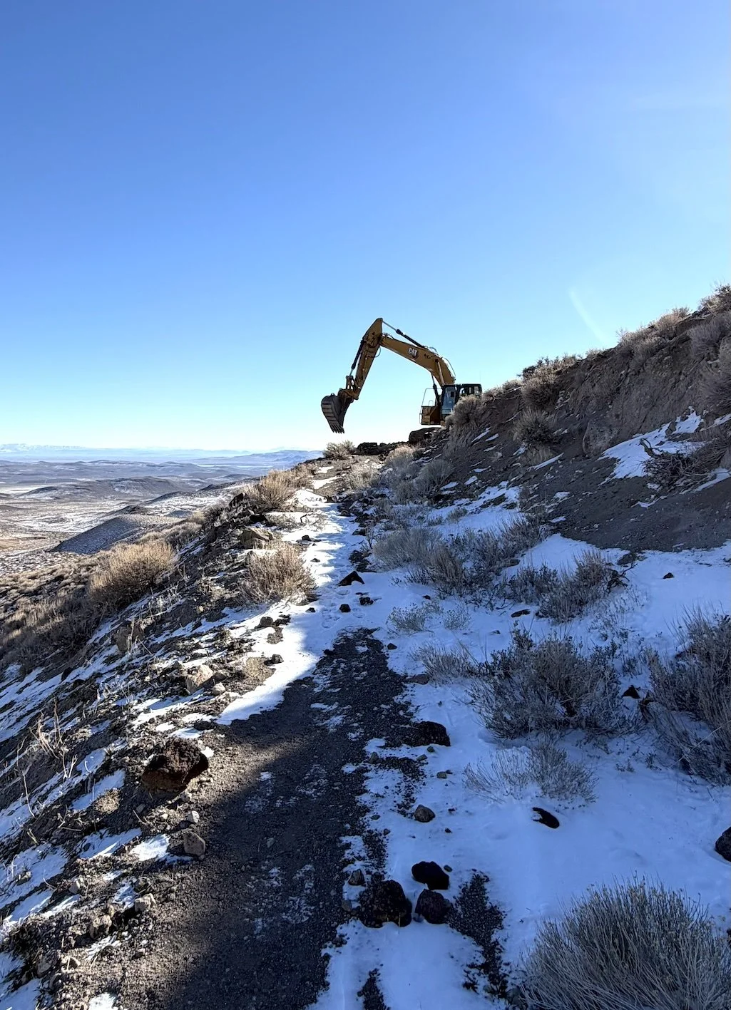 Excavator on a snowy sagebrush hillside in Northern Nevada